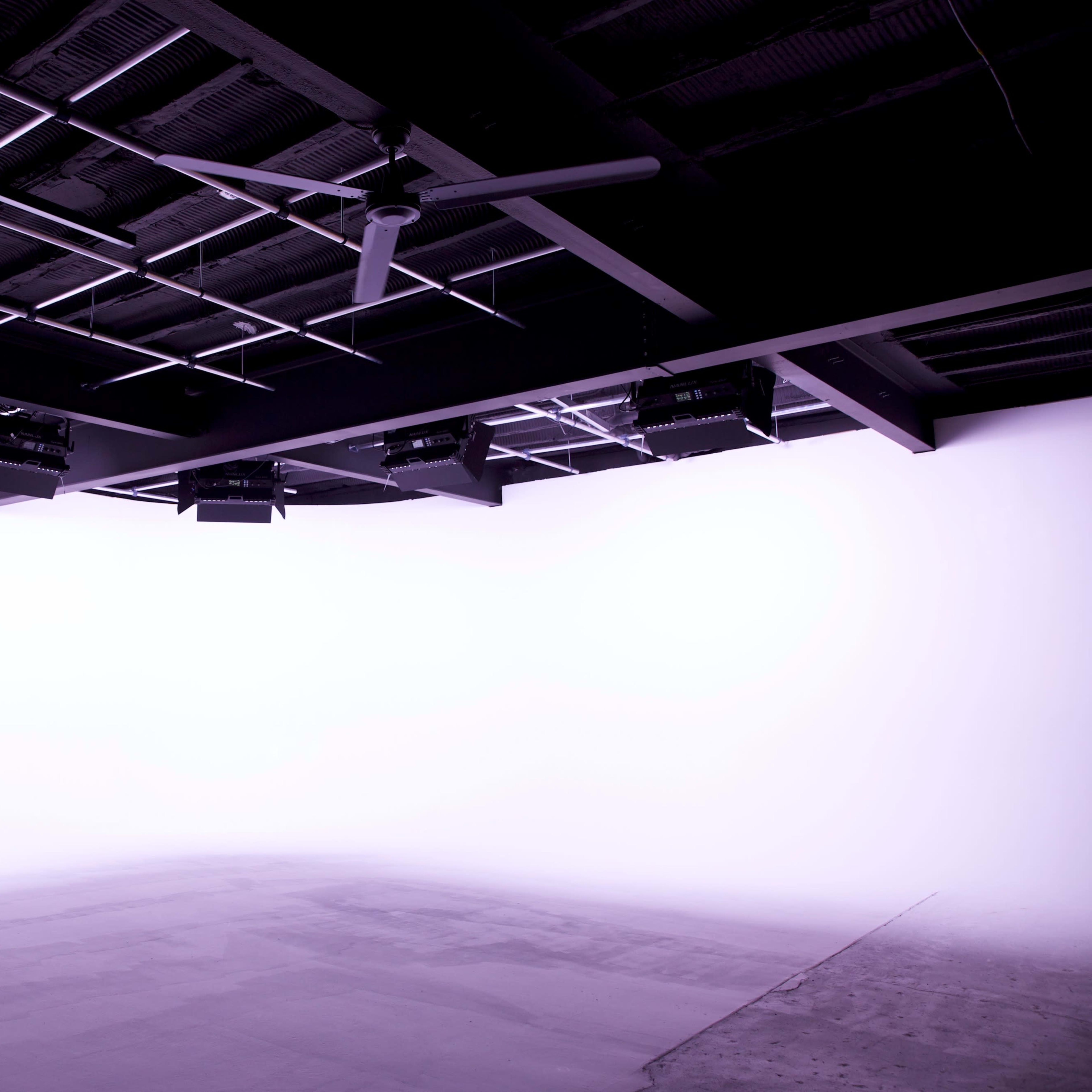 A blank studio space with a smooth floor and minimal lighting equipment installed overhead.