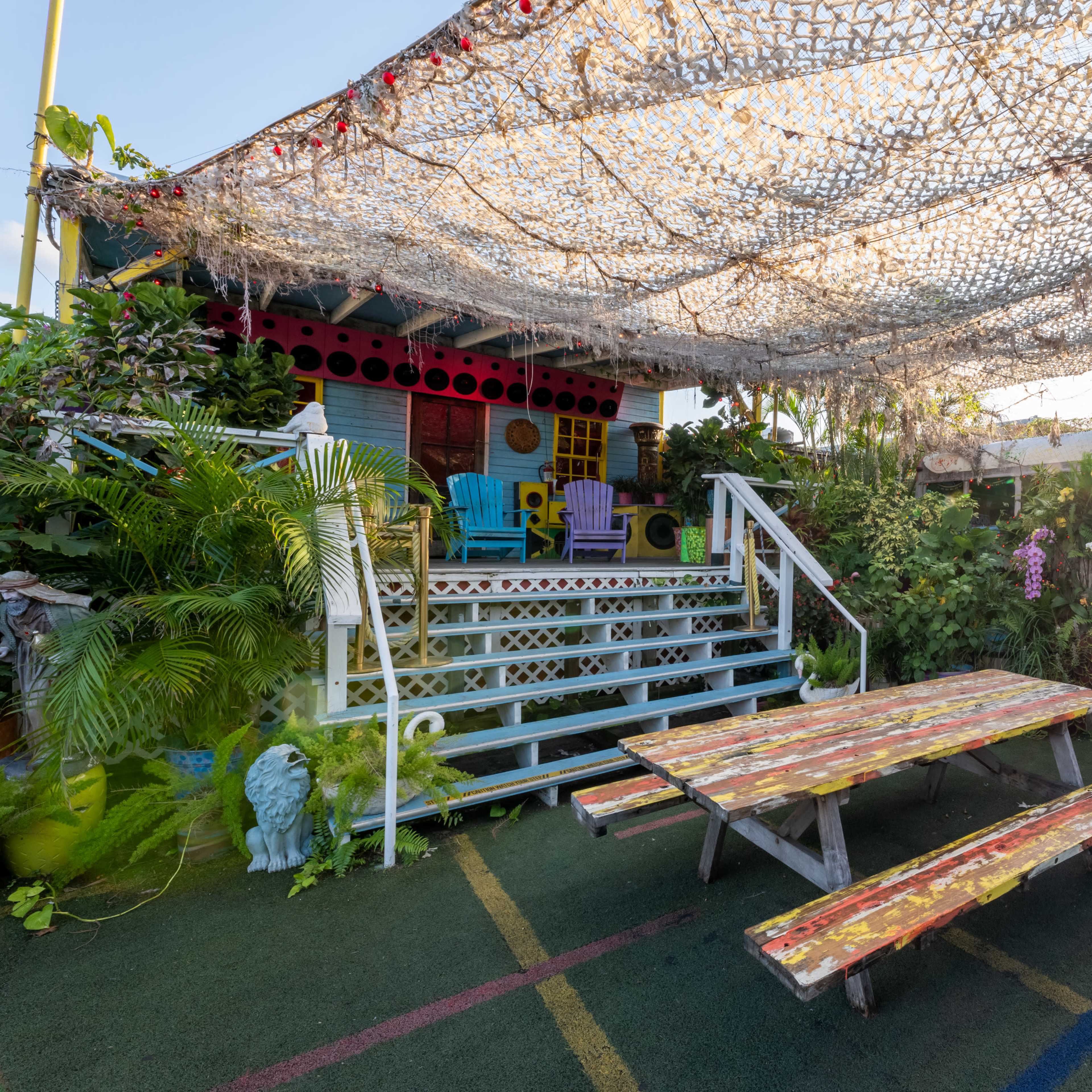 A colorful outdoor seating area features painted benches and a covered space with plants and decorative elements.