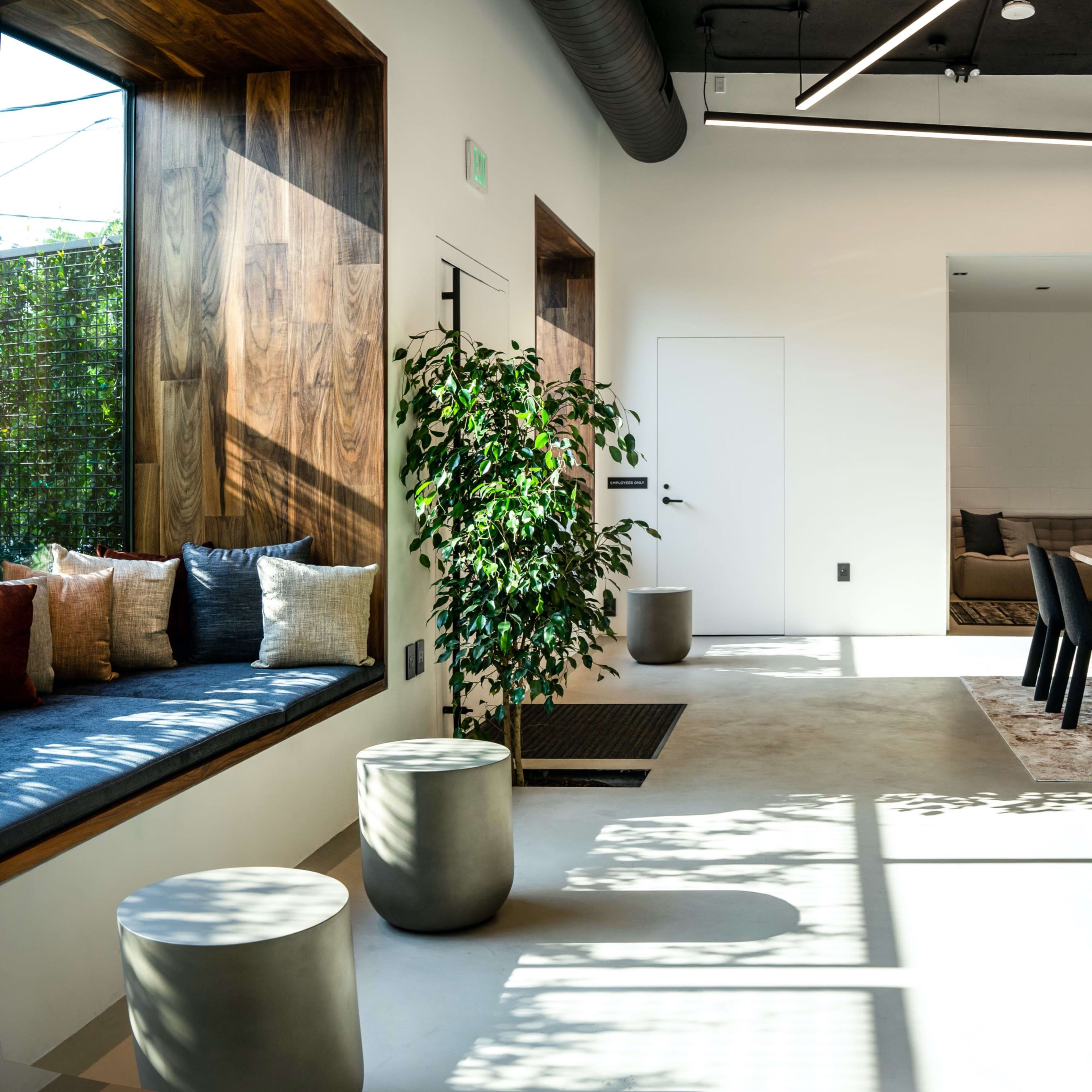 A modern, open-concept living space with a dining area, kitchen, and a cozy seating nook filled with cushions.