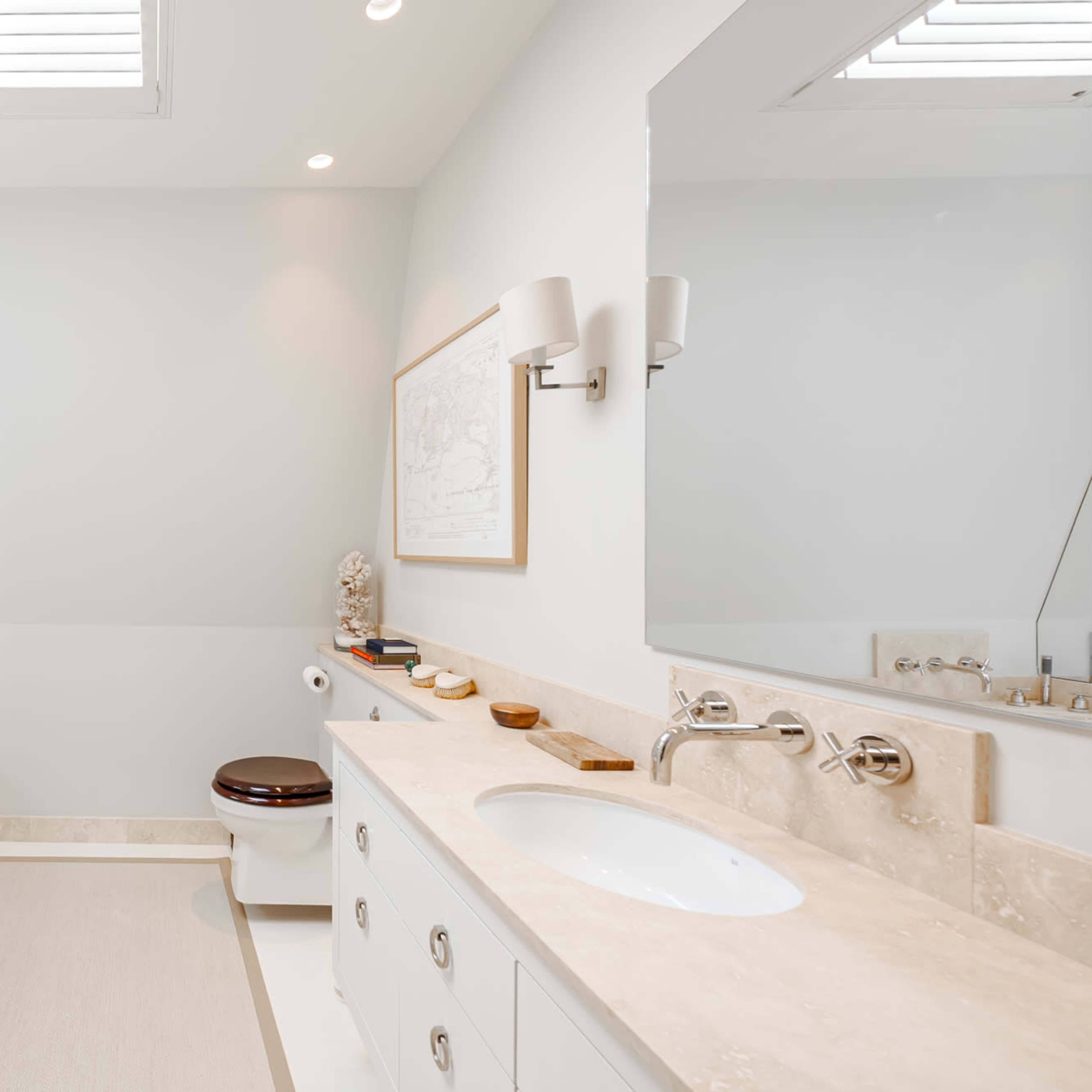 A modern bathroom featuring a bathtub, a separate toilet, dual sinks, and two mirrors.