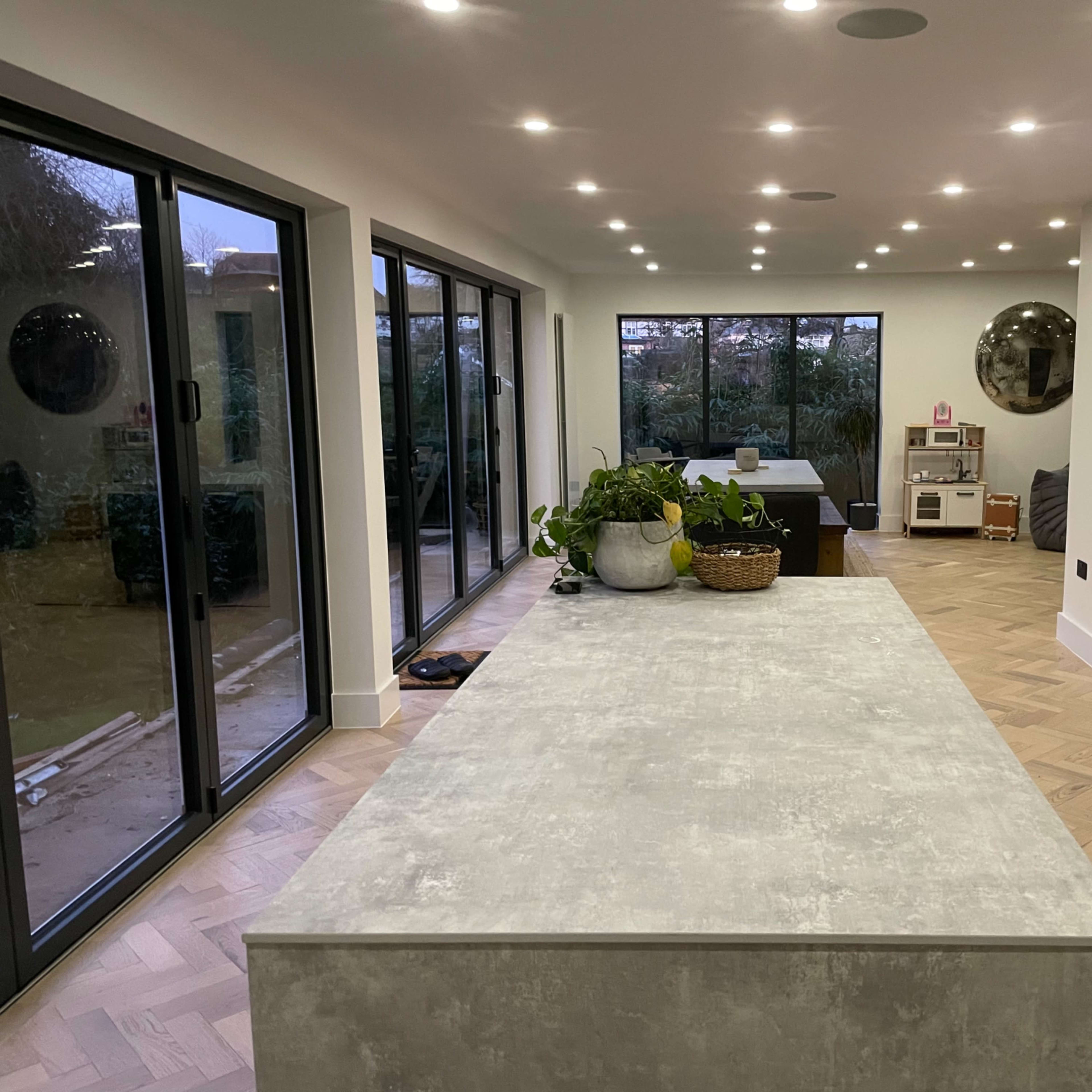 A modern interior with a spacious living area featuring large windows, a central kitchen island, and minimalist decor.