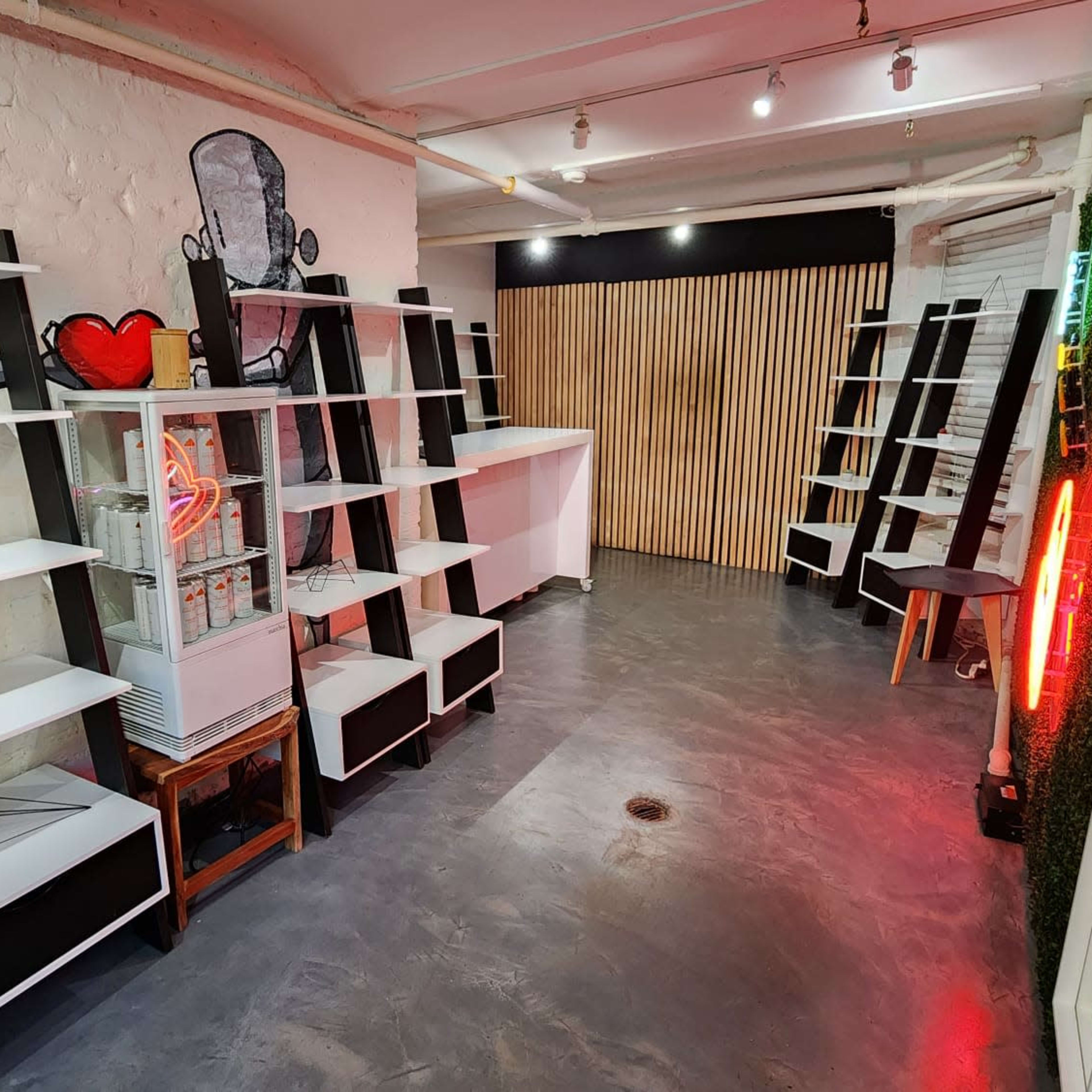 A stylish, empty interior space featuring white shelves along the walls, a glass display case, and a decorative neon light.