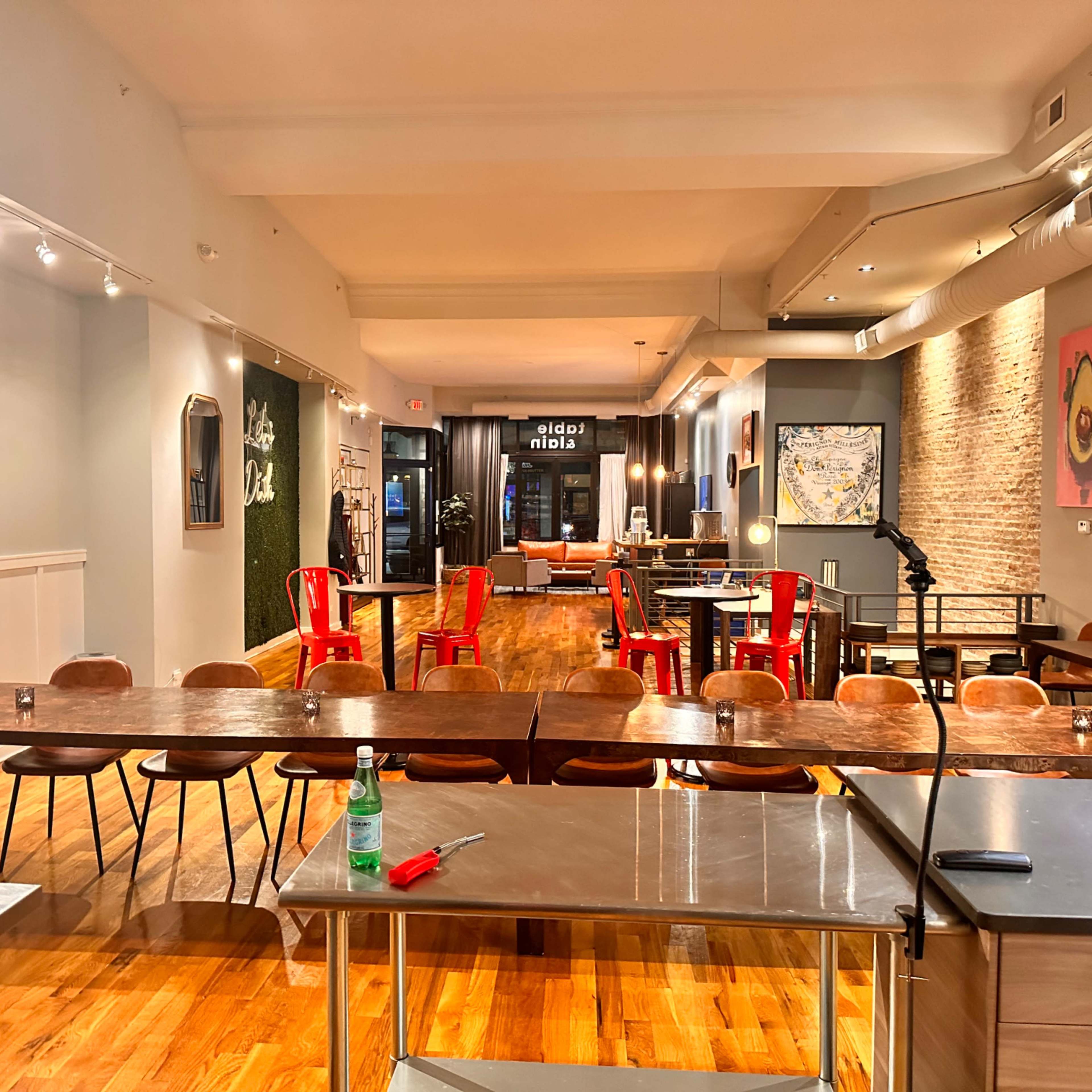 A spacious restaurant with wooden flooring, various tables and chairs, and a large window at the back.