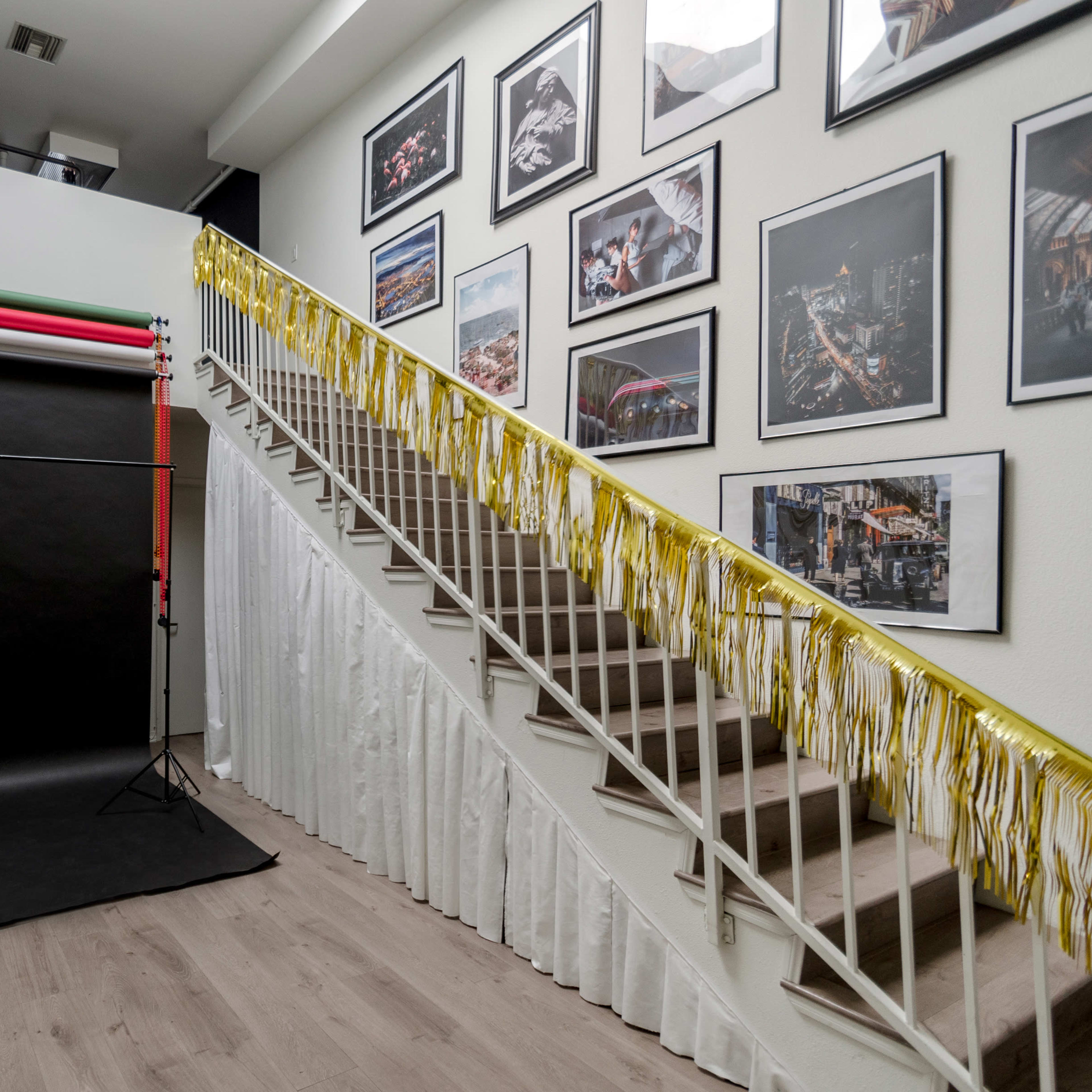 A decorated staircase with a black backdrop and balloons on one side, alongside framed photographs on the wall.