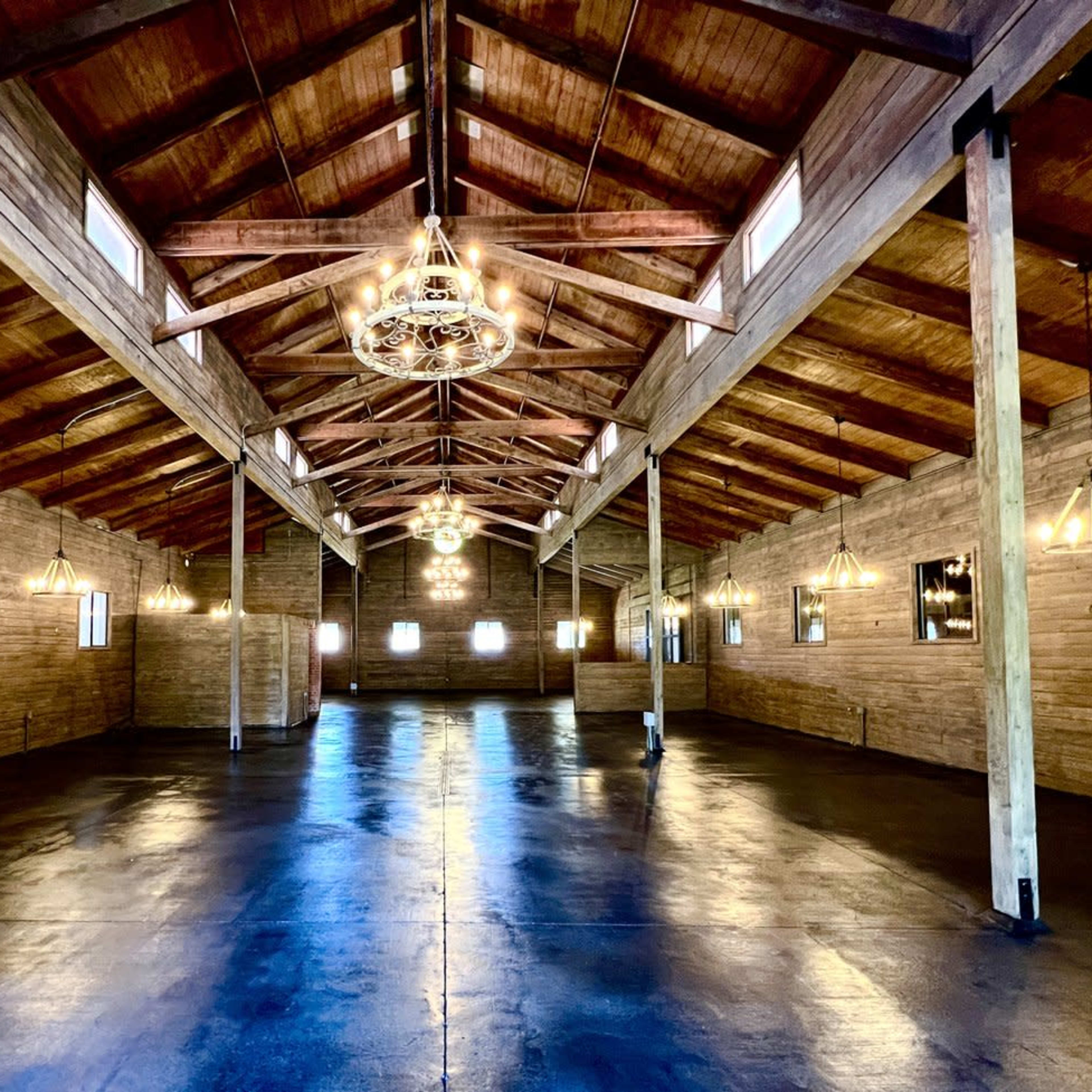 A large, open wooden space with high ceilings, wooden beams, and pendant lighting.