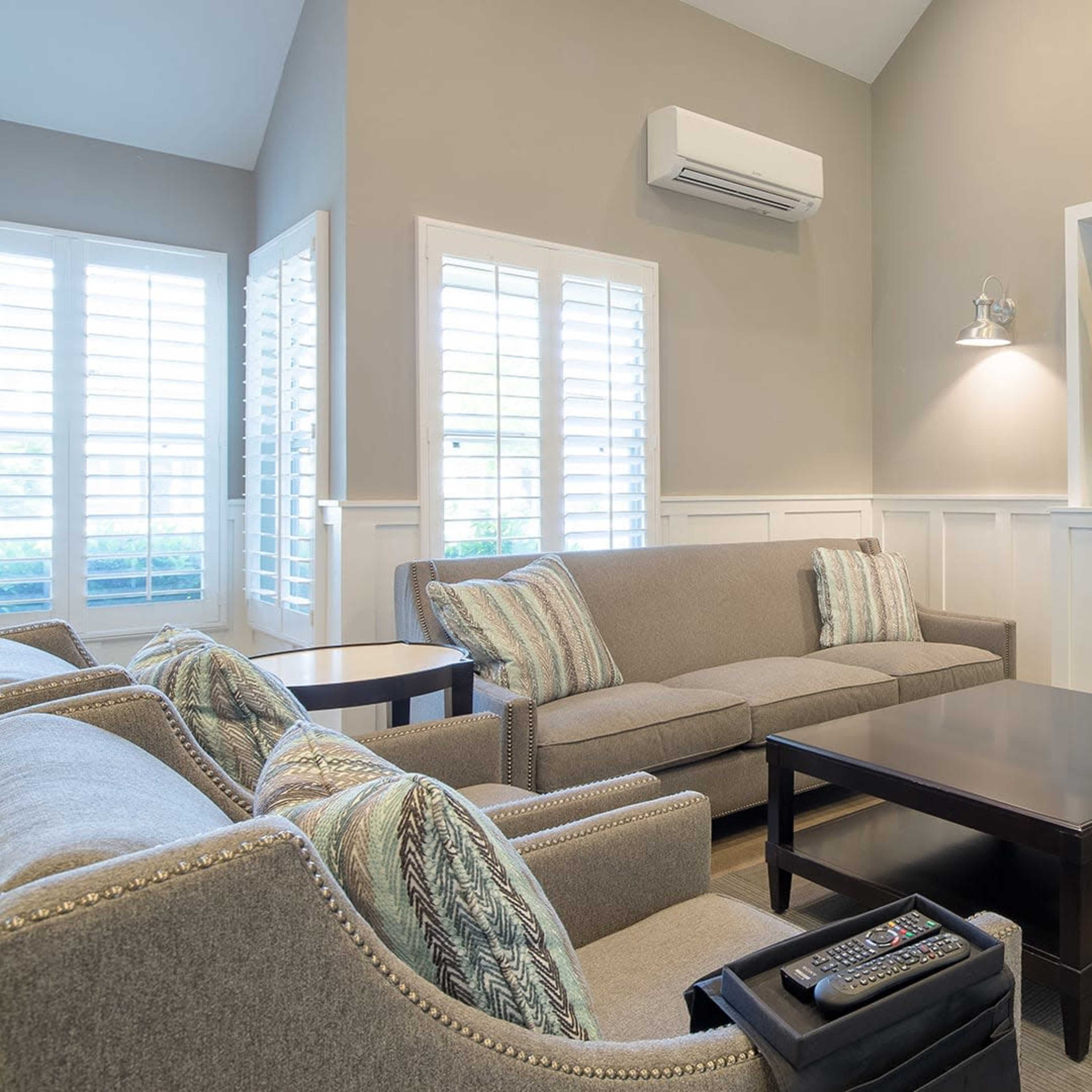 A modern living room with a sofa, armchairs, a coffee table, and a wall-mounted television.