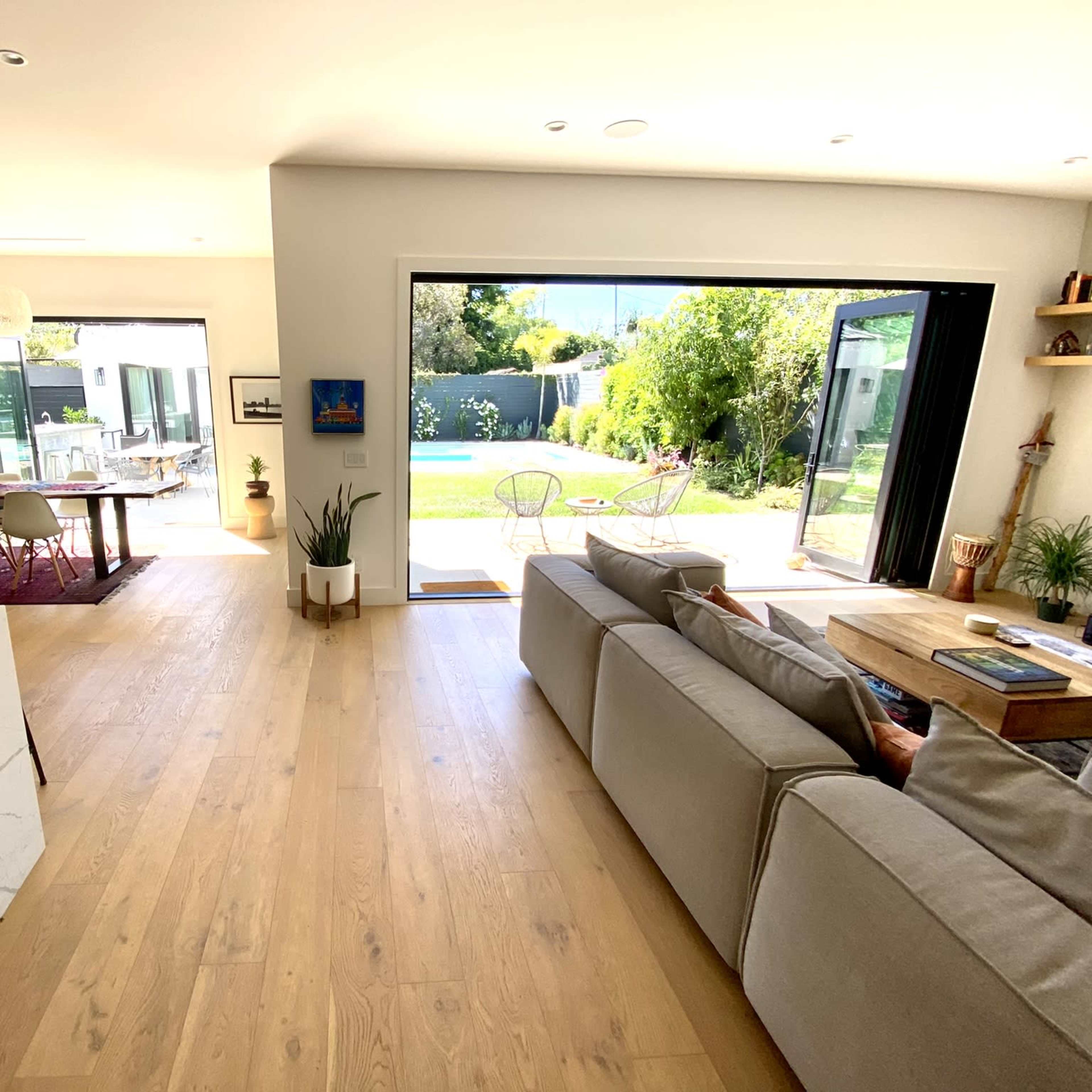 A modern living space with an open layout, featuring a light-filled room connected to a patio and a pool area visible through large sliding glass doors.
