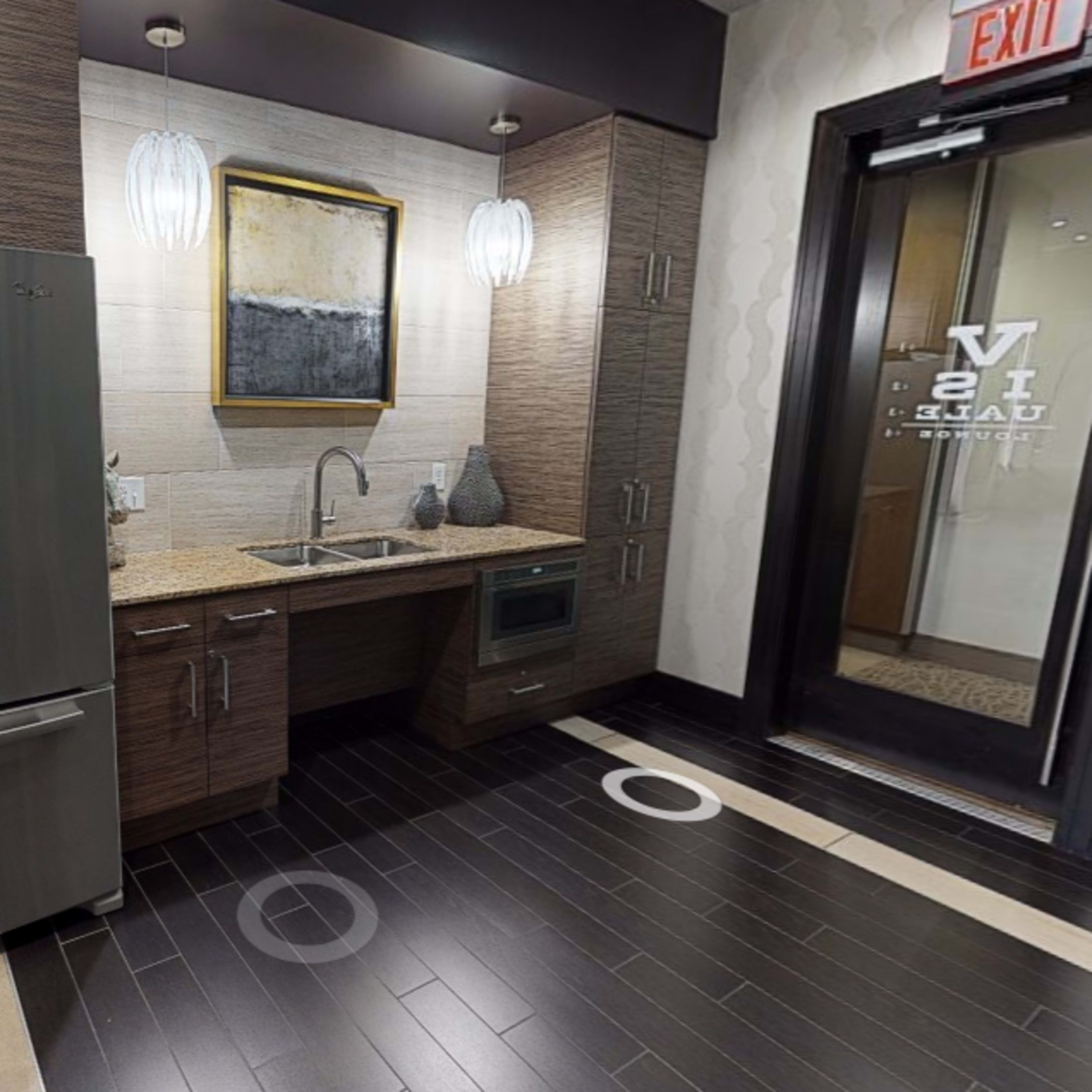 A modern kitchen area featuring stainless steel appliances, granite countertops, and a sleek design with dark wood cabinetry.