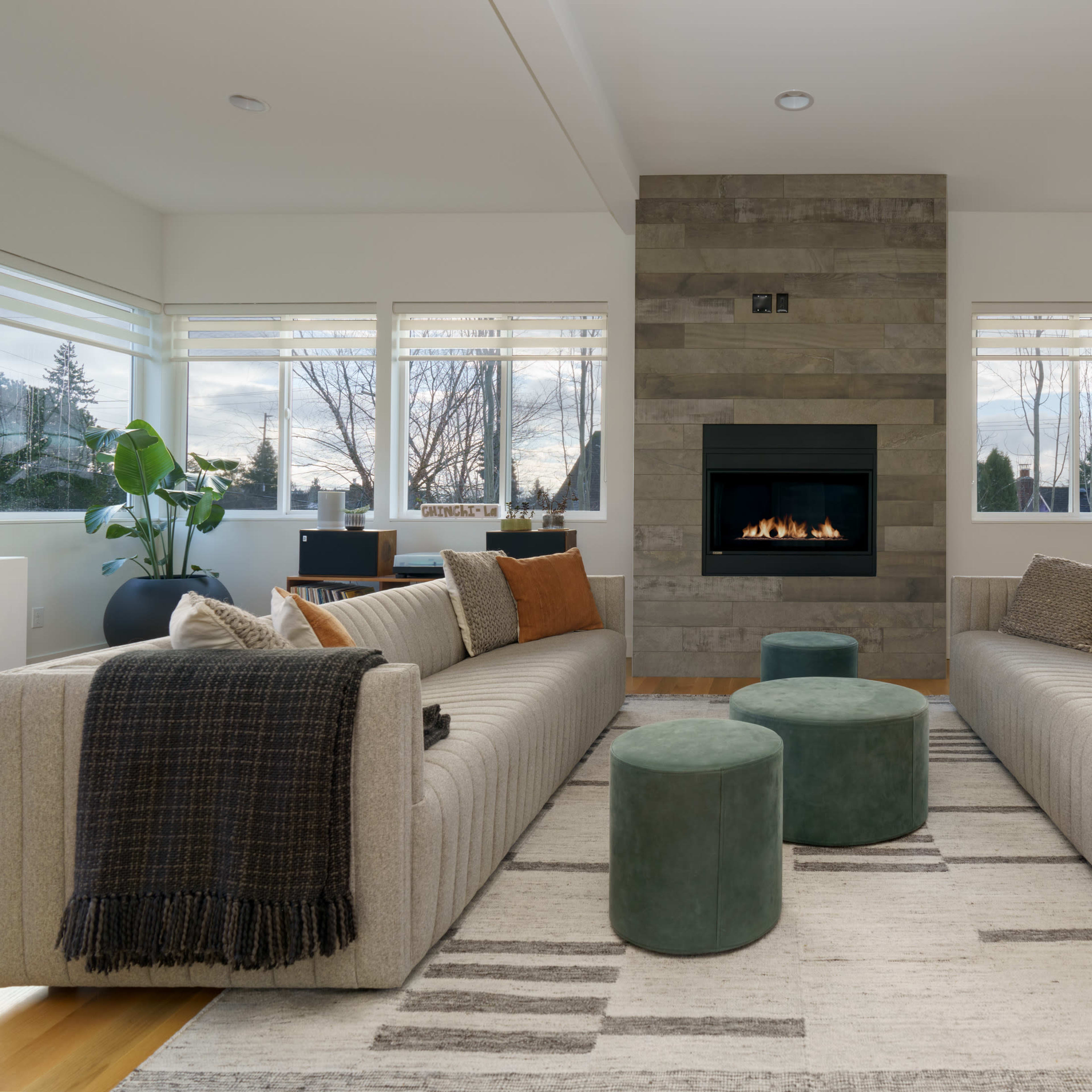 A modern living room with two sofas facing each other, a fireplace in the center wall, and a dining area visible in the background.