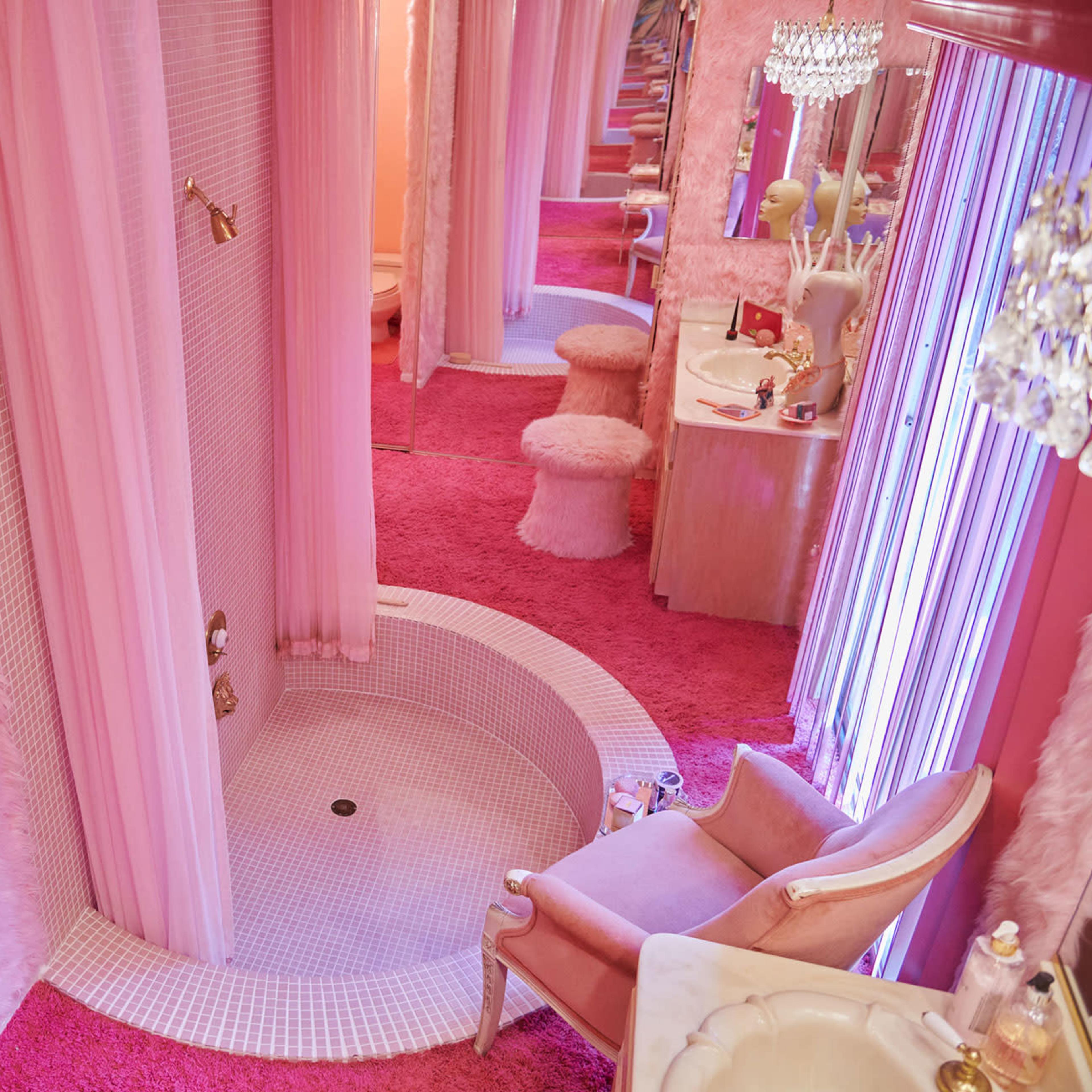 A lavish bathroom with pink fur accents, a circular tiled shower, and plush furnishings.
