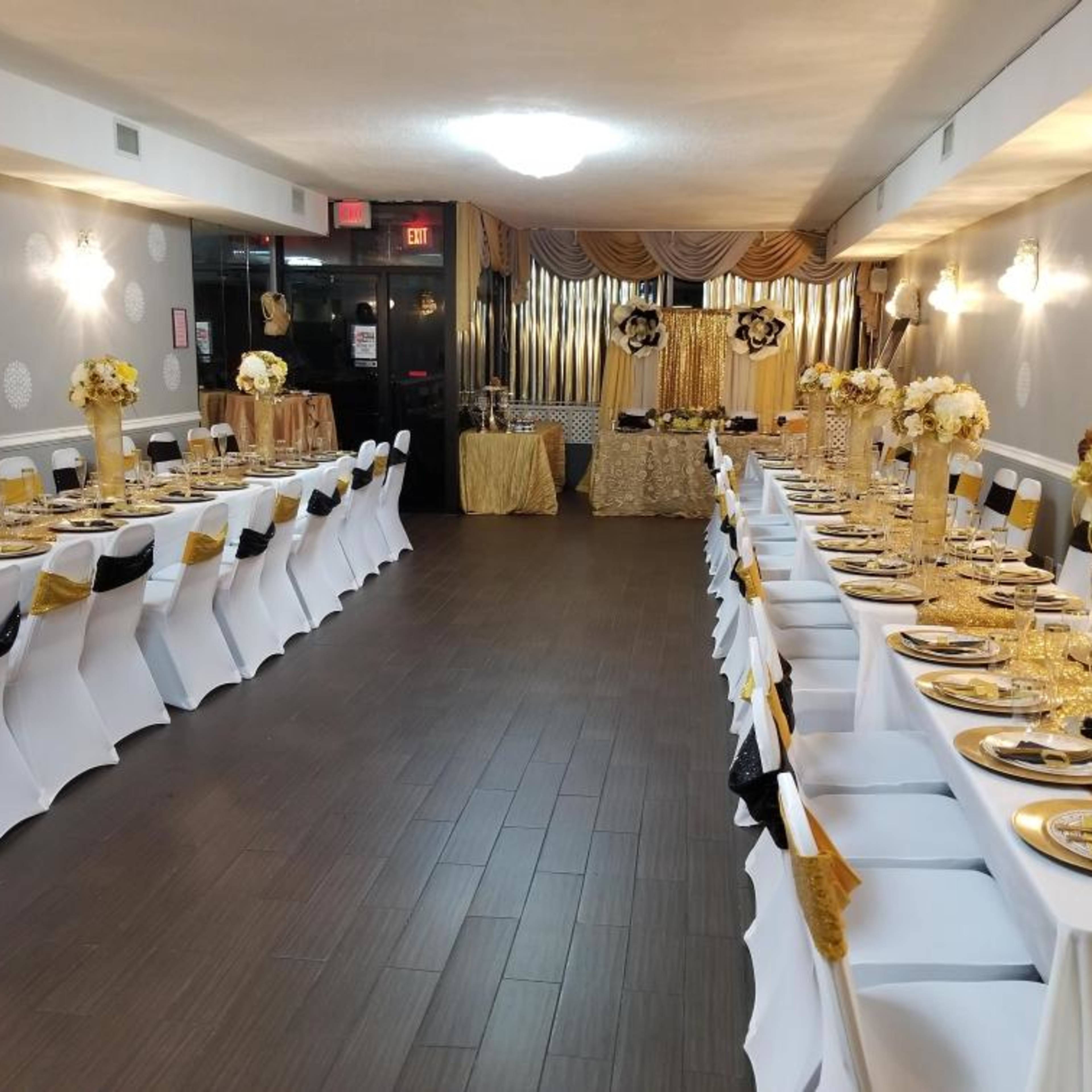 A banquet hall arranged with two long tables set with elegant tableware and decorated with floral centerpieces.