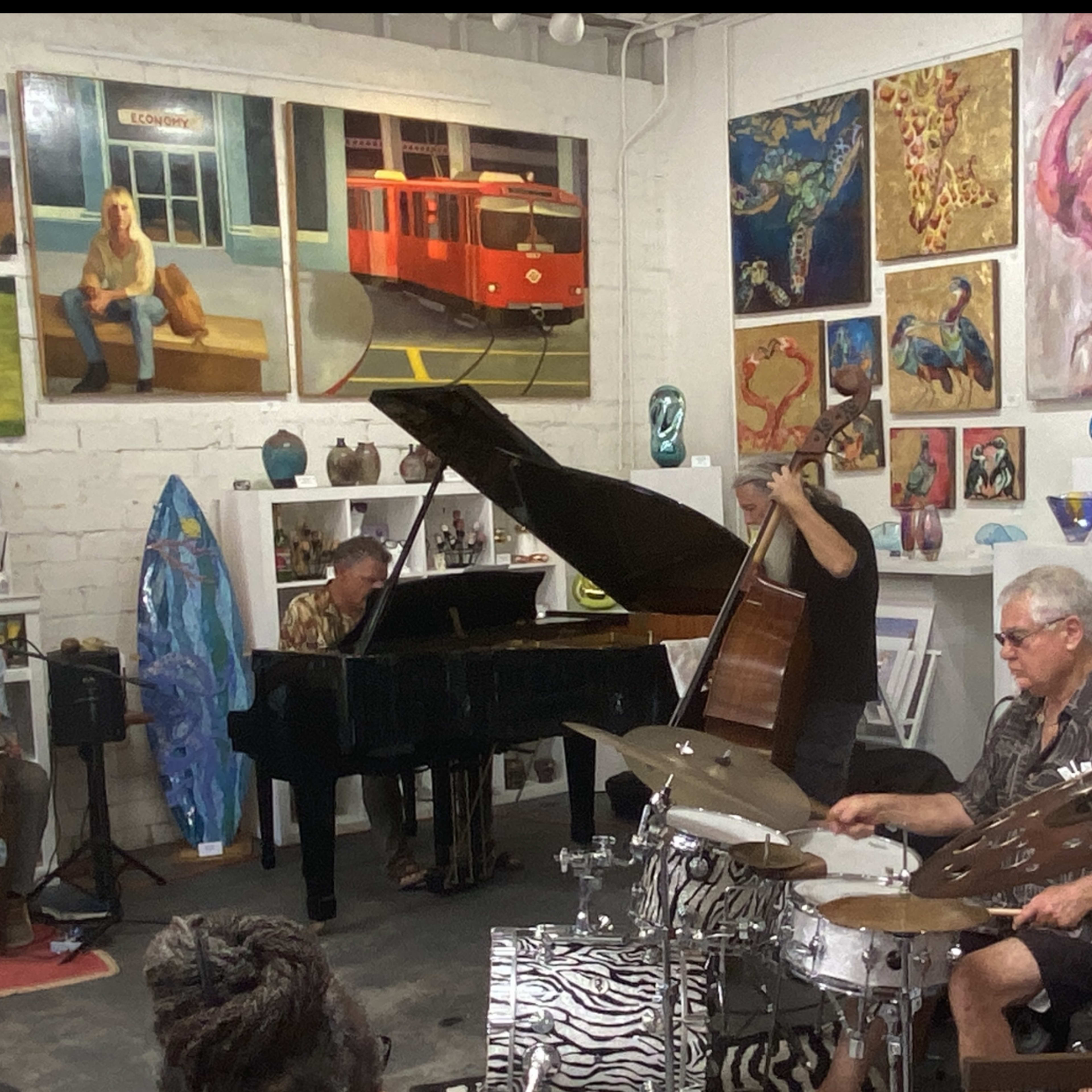 A group of musicians performs in an art gallery decorated with various paintings and sculptures.