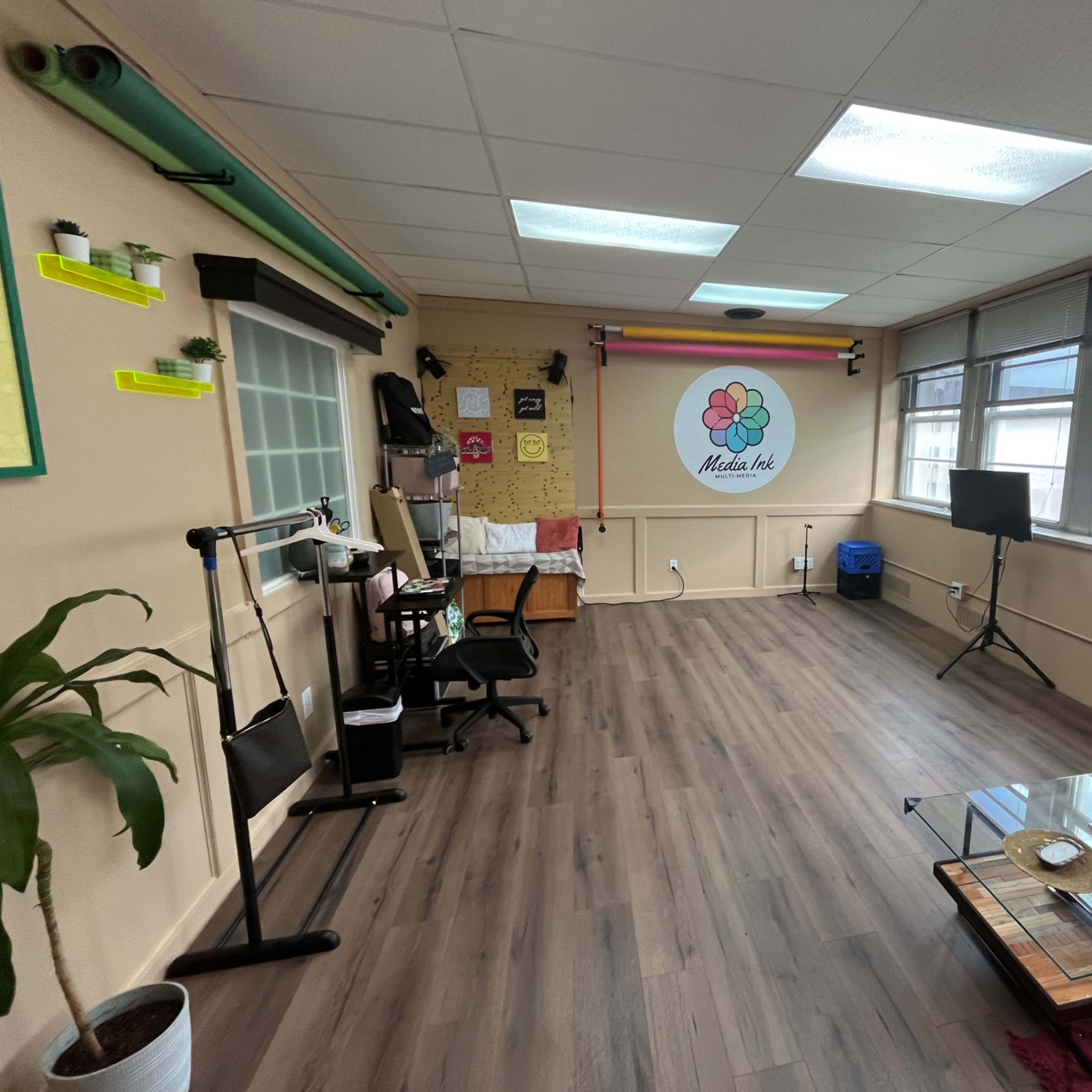 A spacious, well-lit room with a seating area, a small table with fruit, and colorful wall decor.