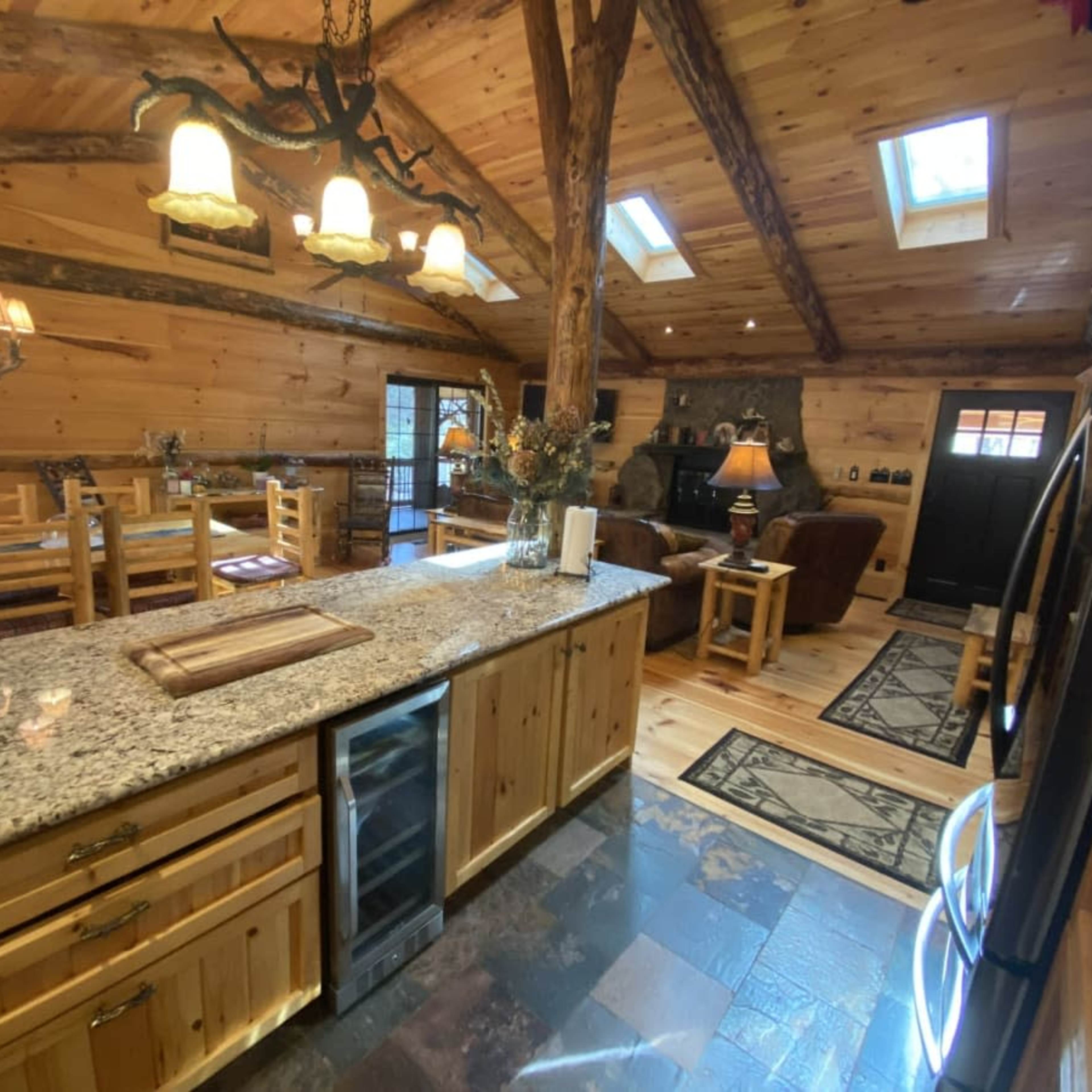 A rustic kitchen with wooden cabinetry, a granite countertop, and an open layout connected to a dining area and living space.