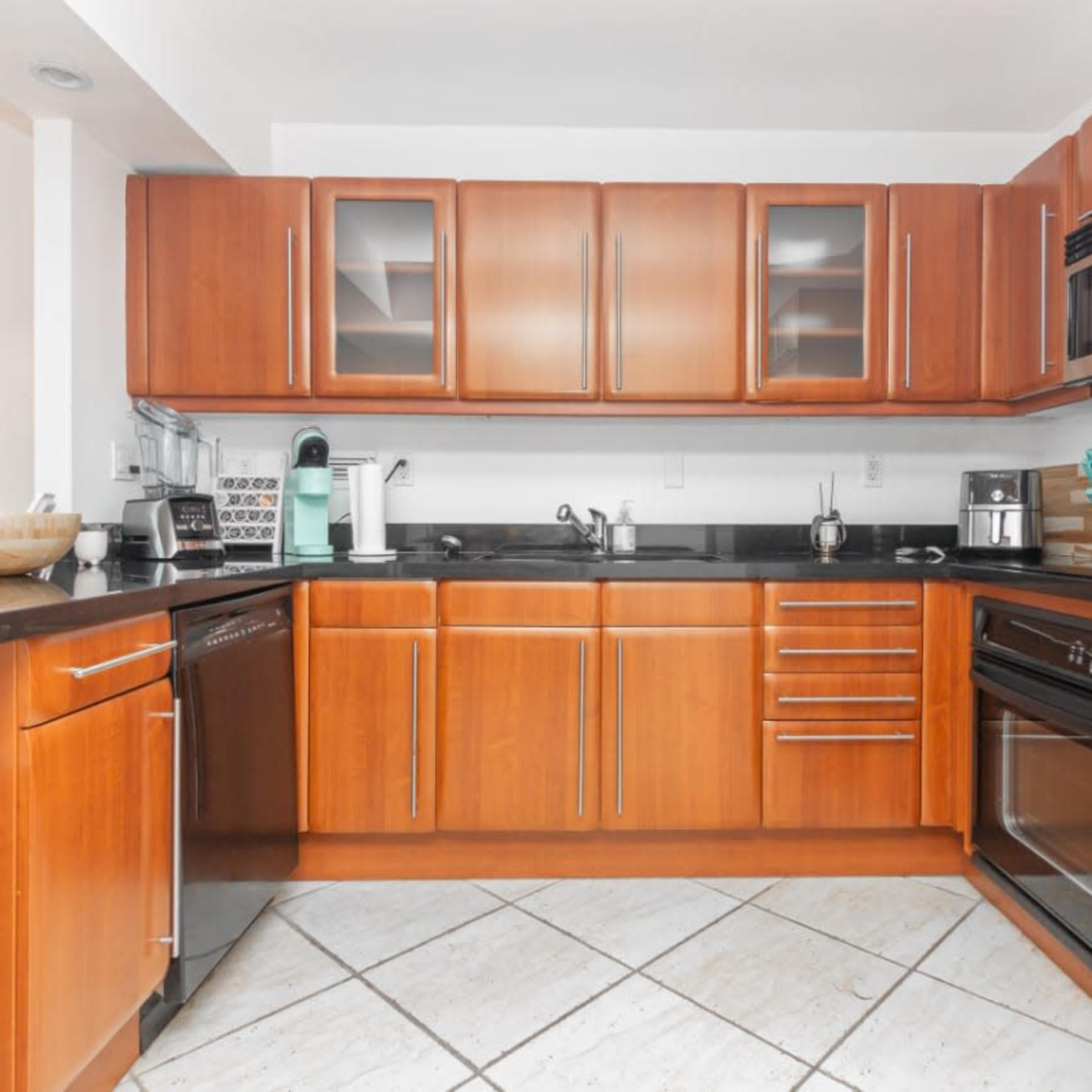 A modern kitchen with wooden cabinetry, stainless steel appliances, and a black countertop.