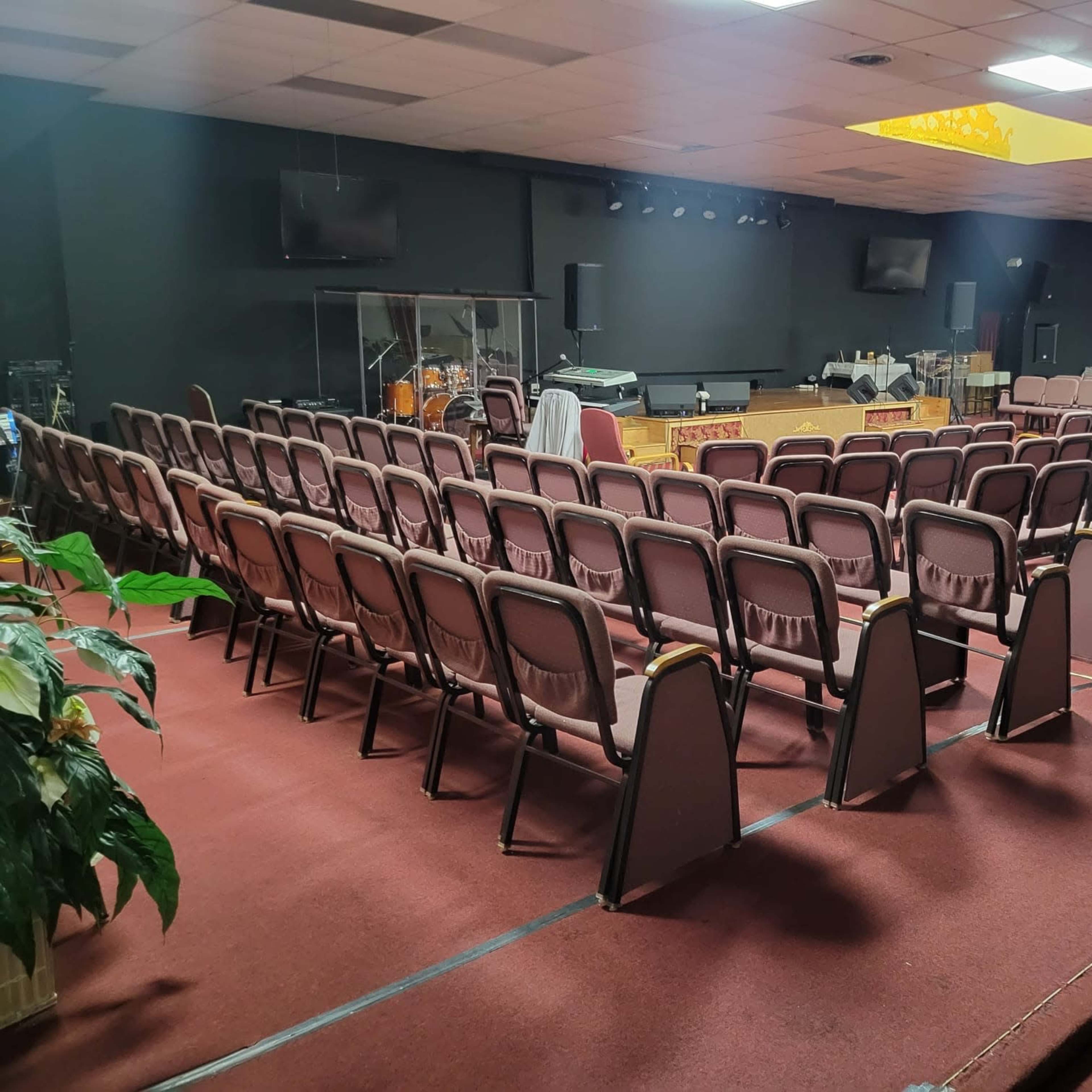 A church auditorium with rows of empty chairs facing a stage and musical instruments in the background.