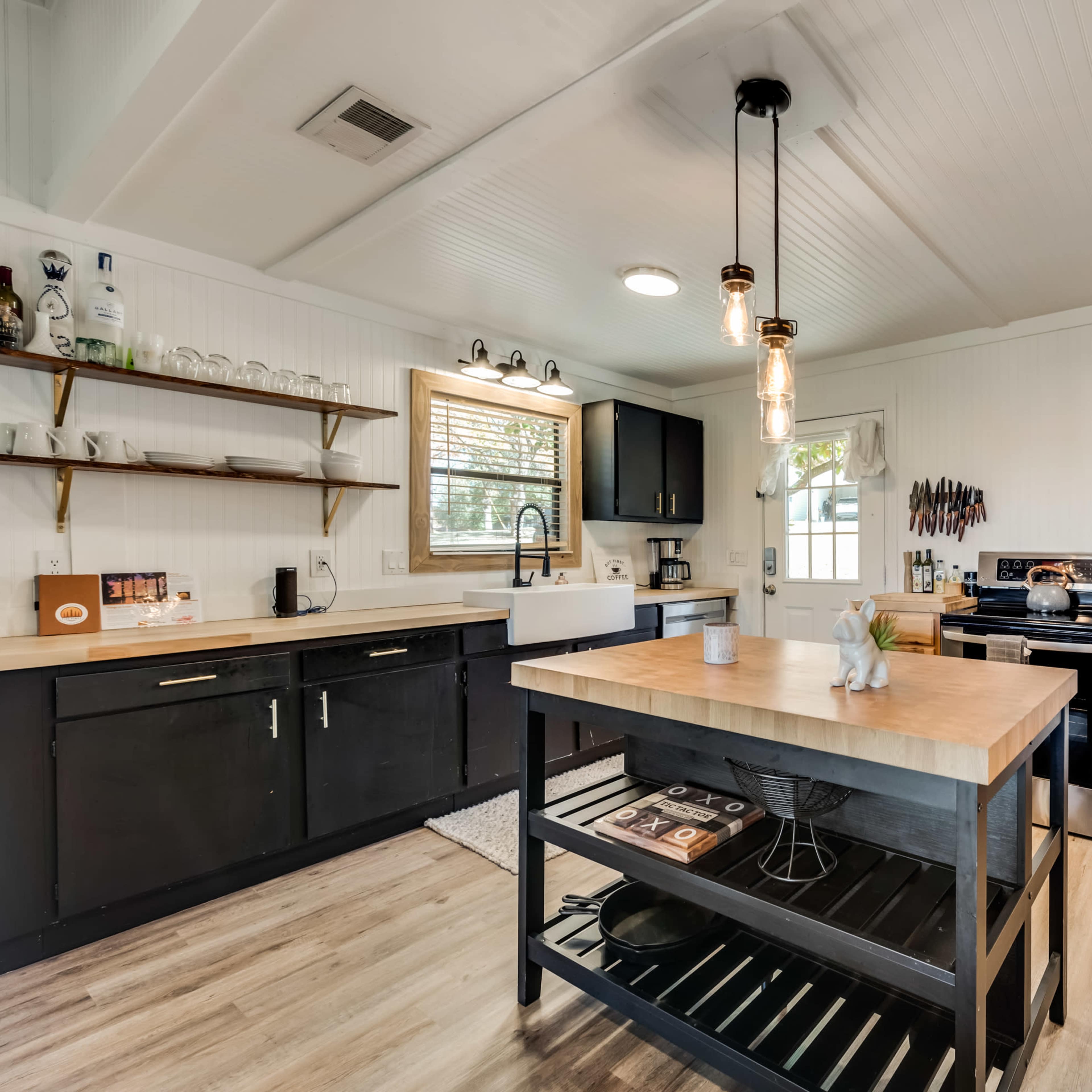 A modern kitchen with black cabinetry, a central wooden island, and stainless steel appliances.