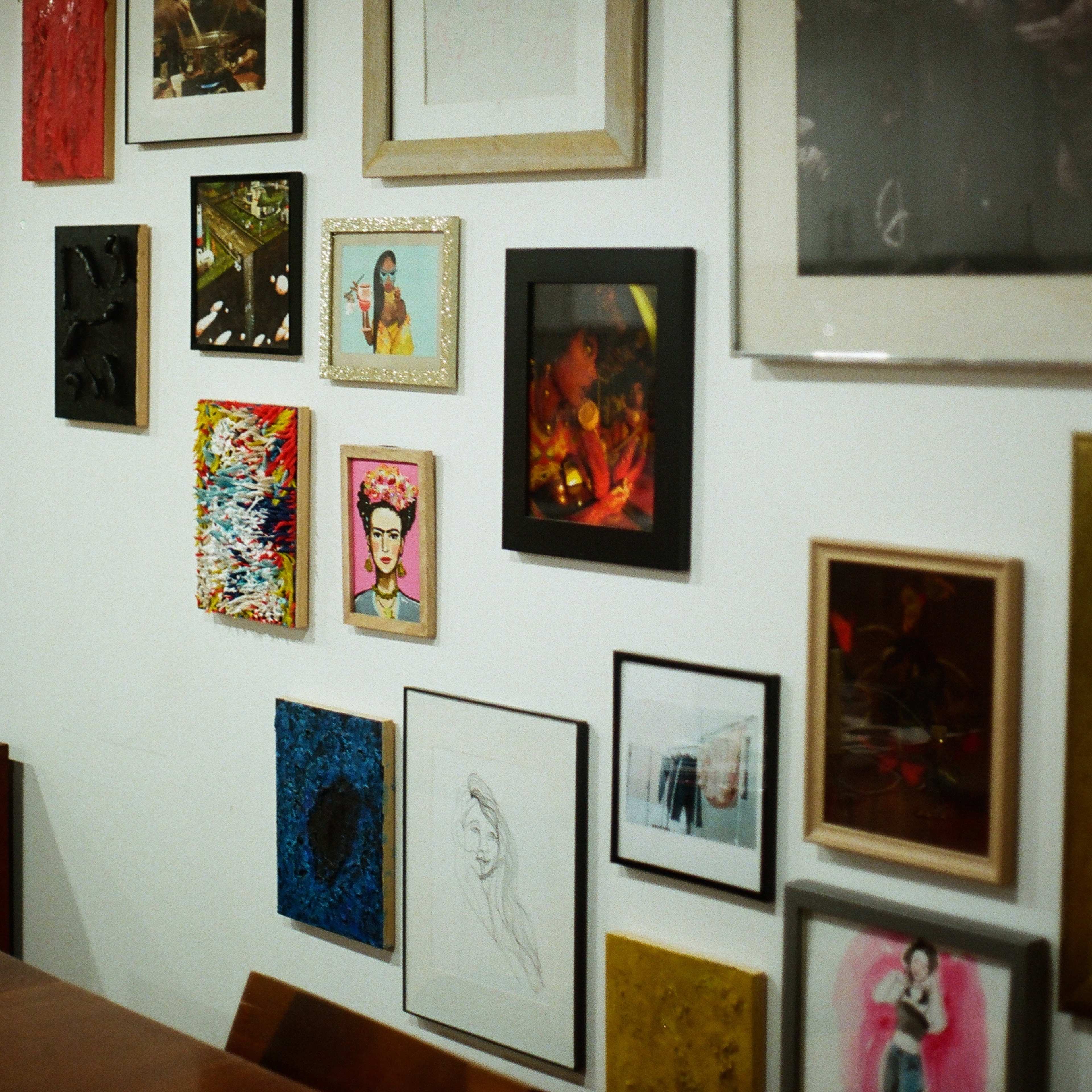 A wall adorned with a variety of framed artworks, including photographs and paintings, arranged in an eclectic display.