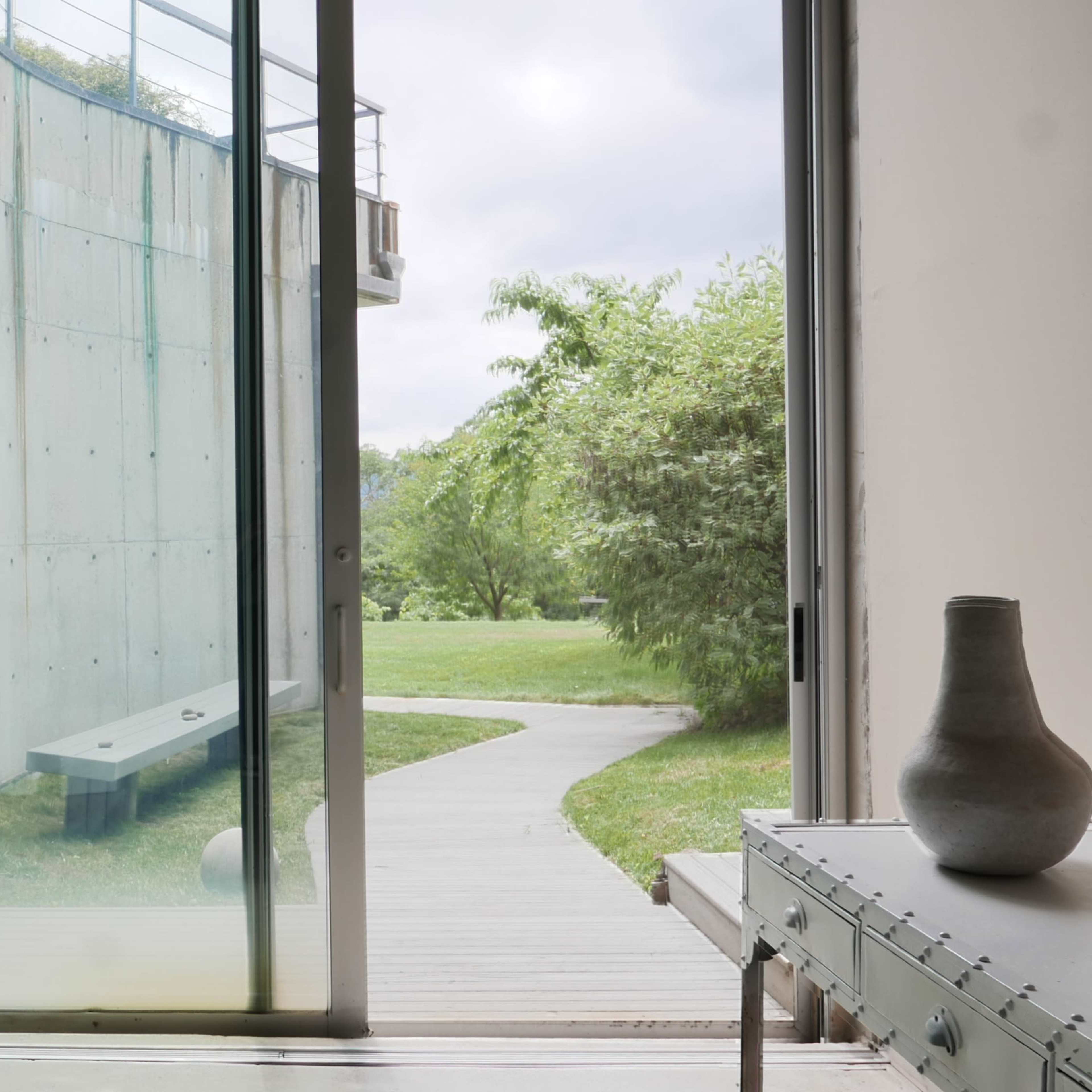 A view of a modern architectural space with large glass doors opening to a green garden and pathway.