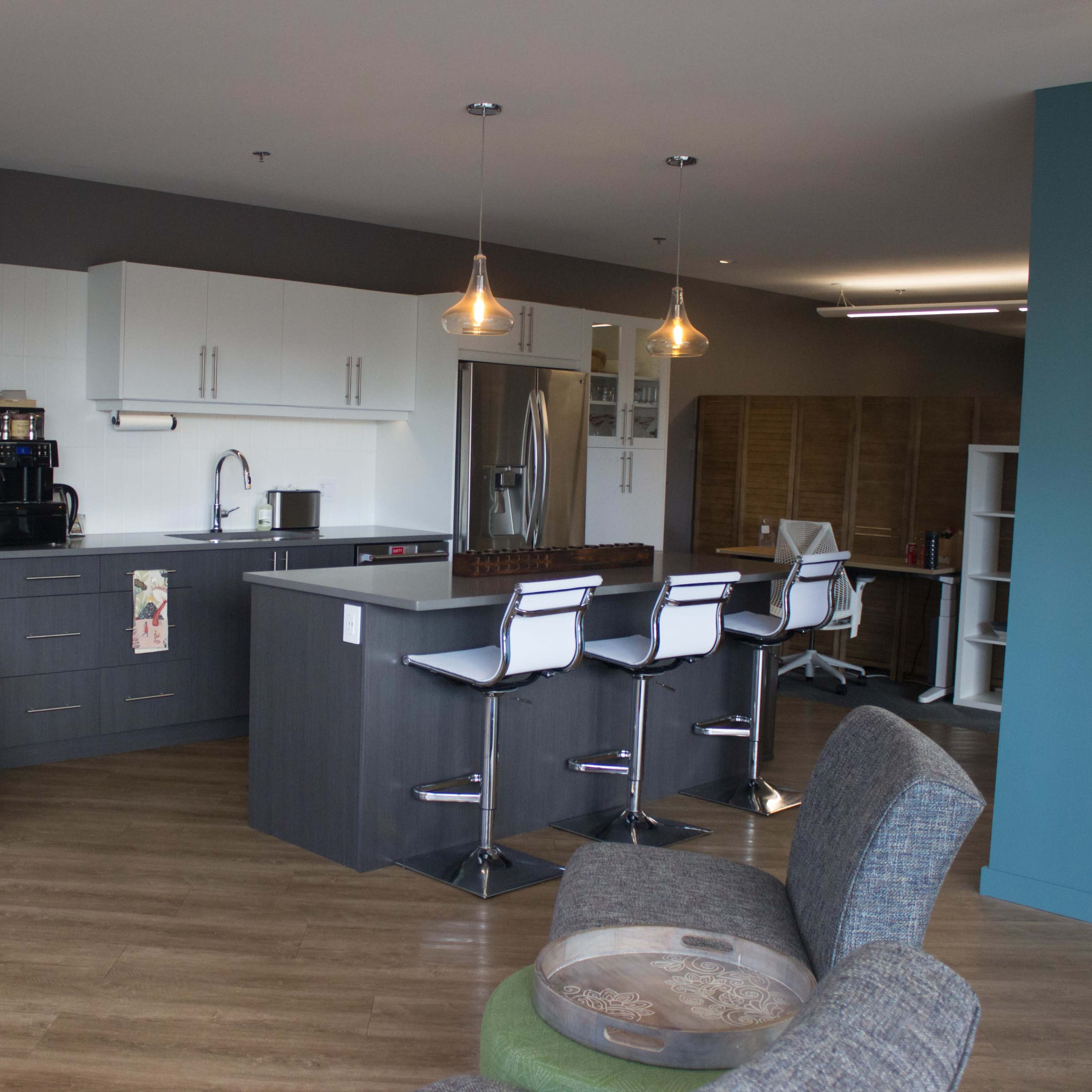 A modern kitchen and lounge area with a countertop, bar stools, and a seating arrangement.