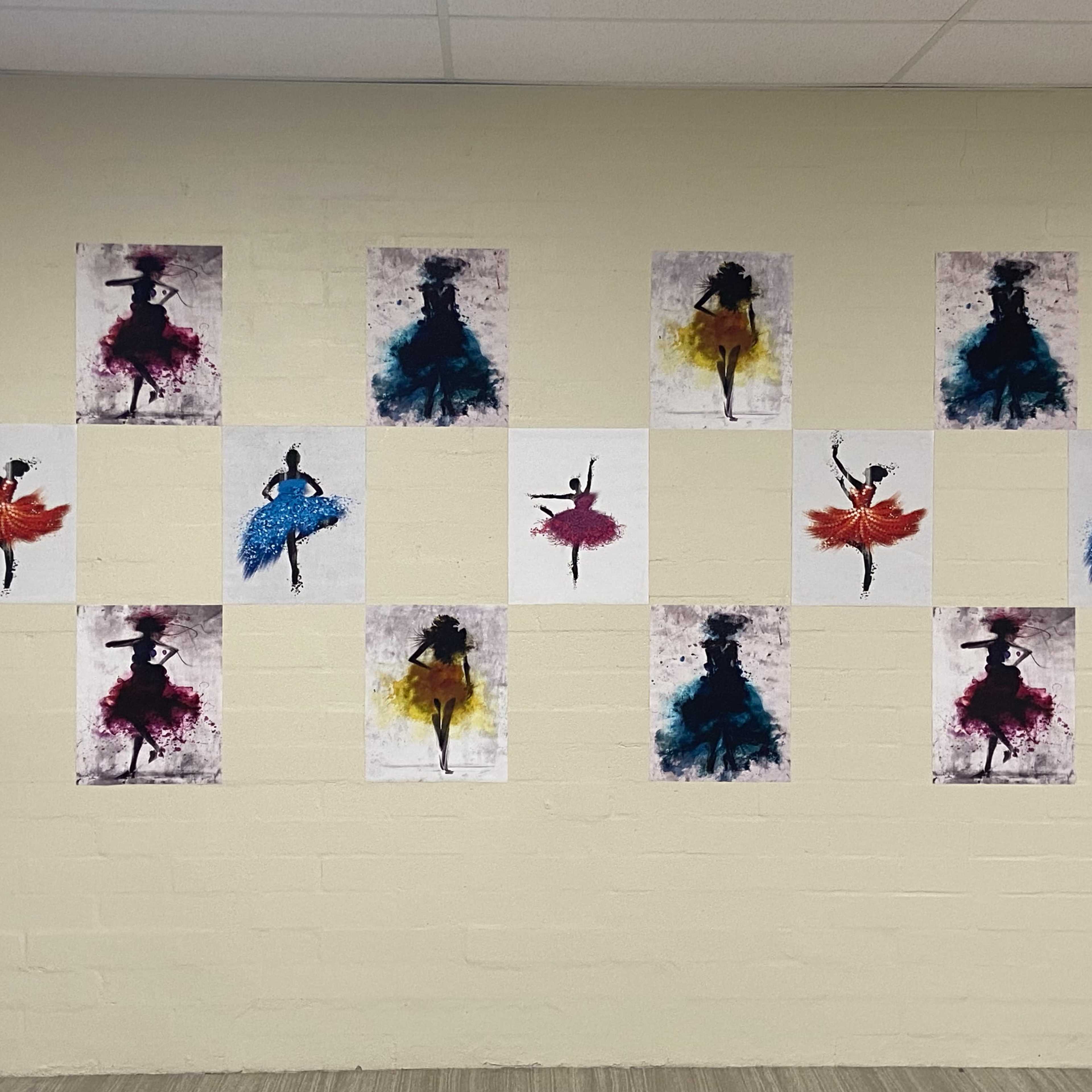 A wall decorated with several framed artworks depicting silhouetted dancers in various colored dresses.