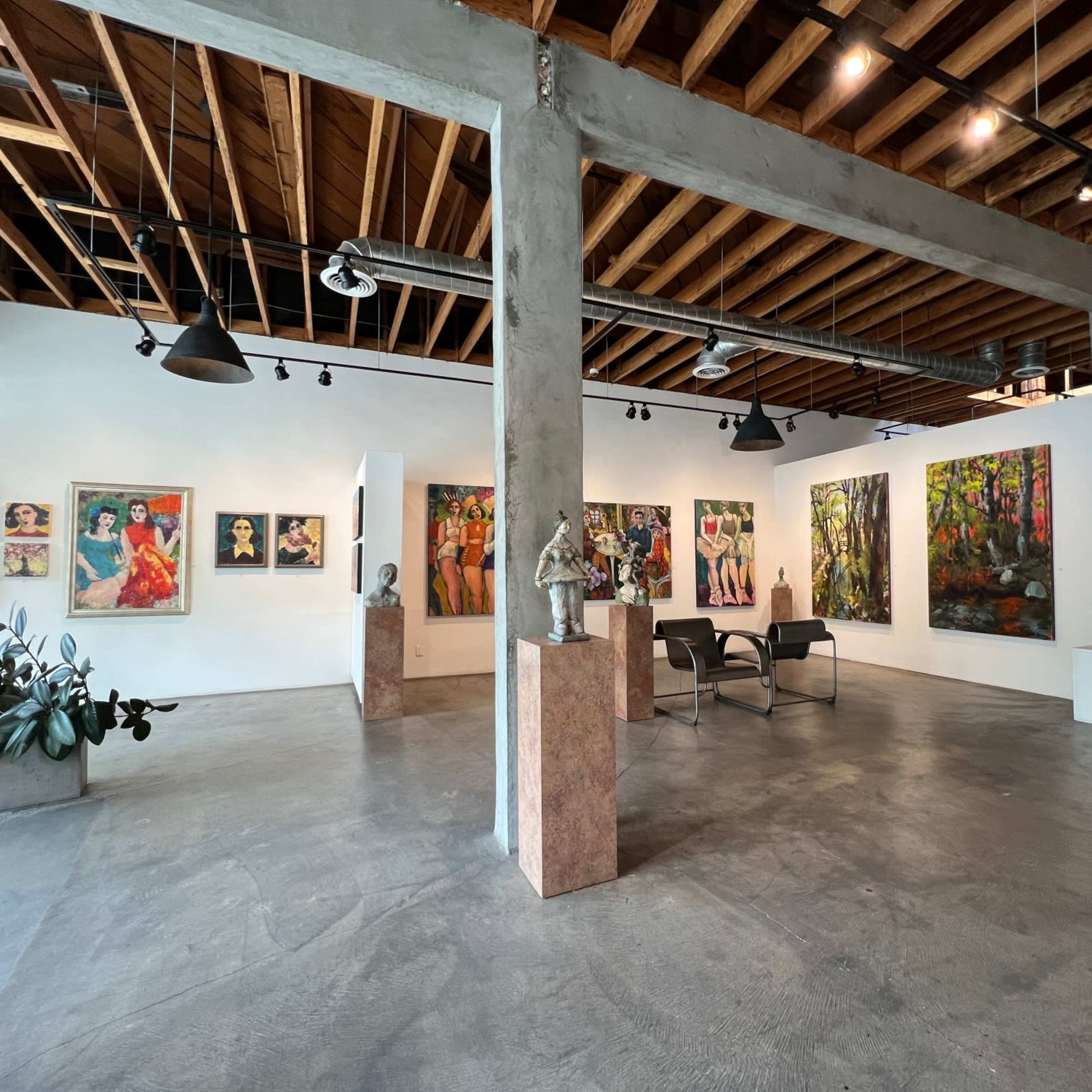 An art gallery featuring various paintings on the walls, sculptures in the center, and open space with a polished concrete floor.