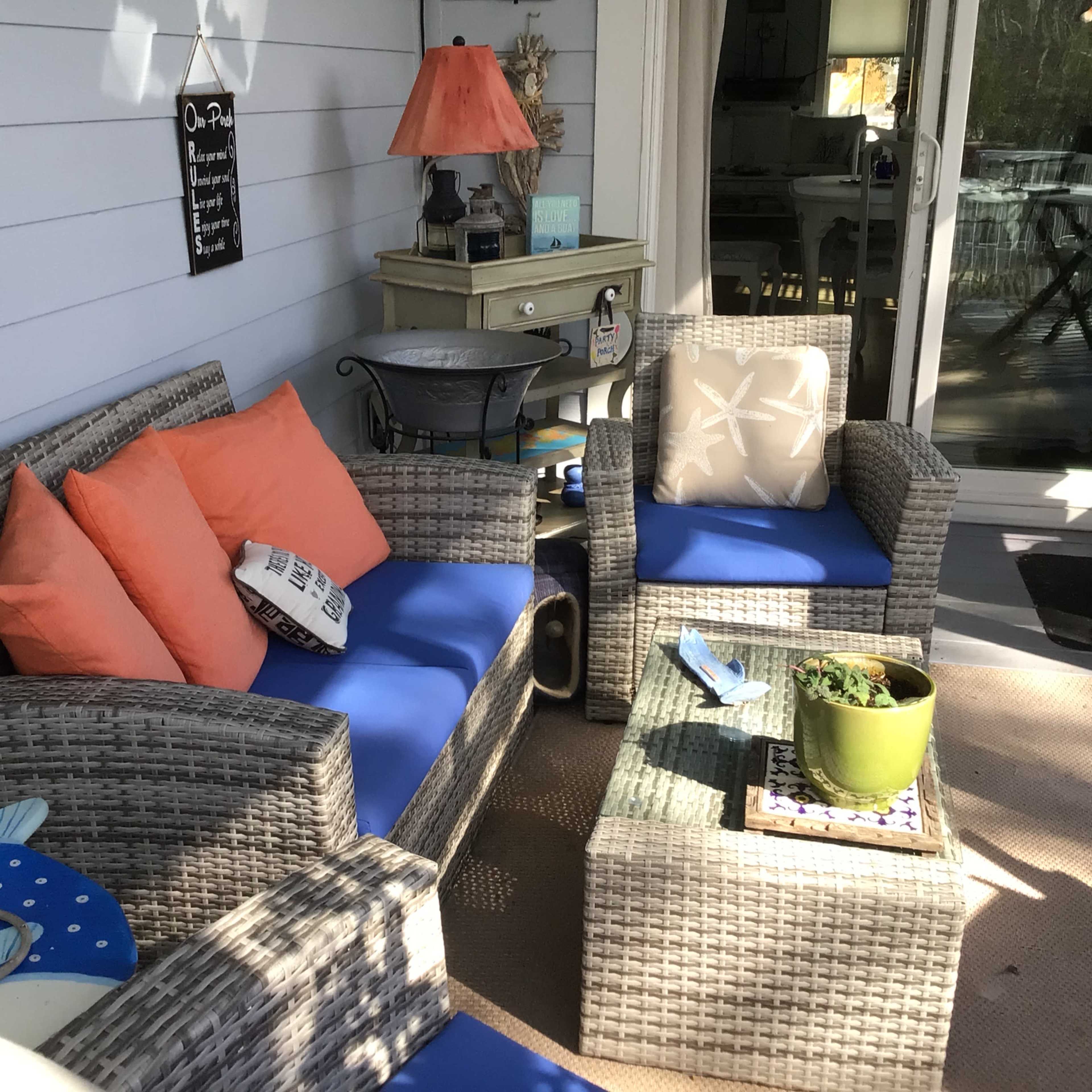 A cozy outdoor seating area with wicker furniture, blue cushions, and a small table topped with a green plant and decorative items.