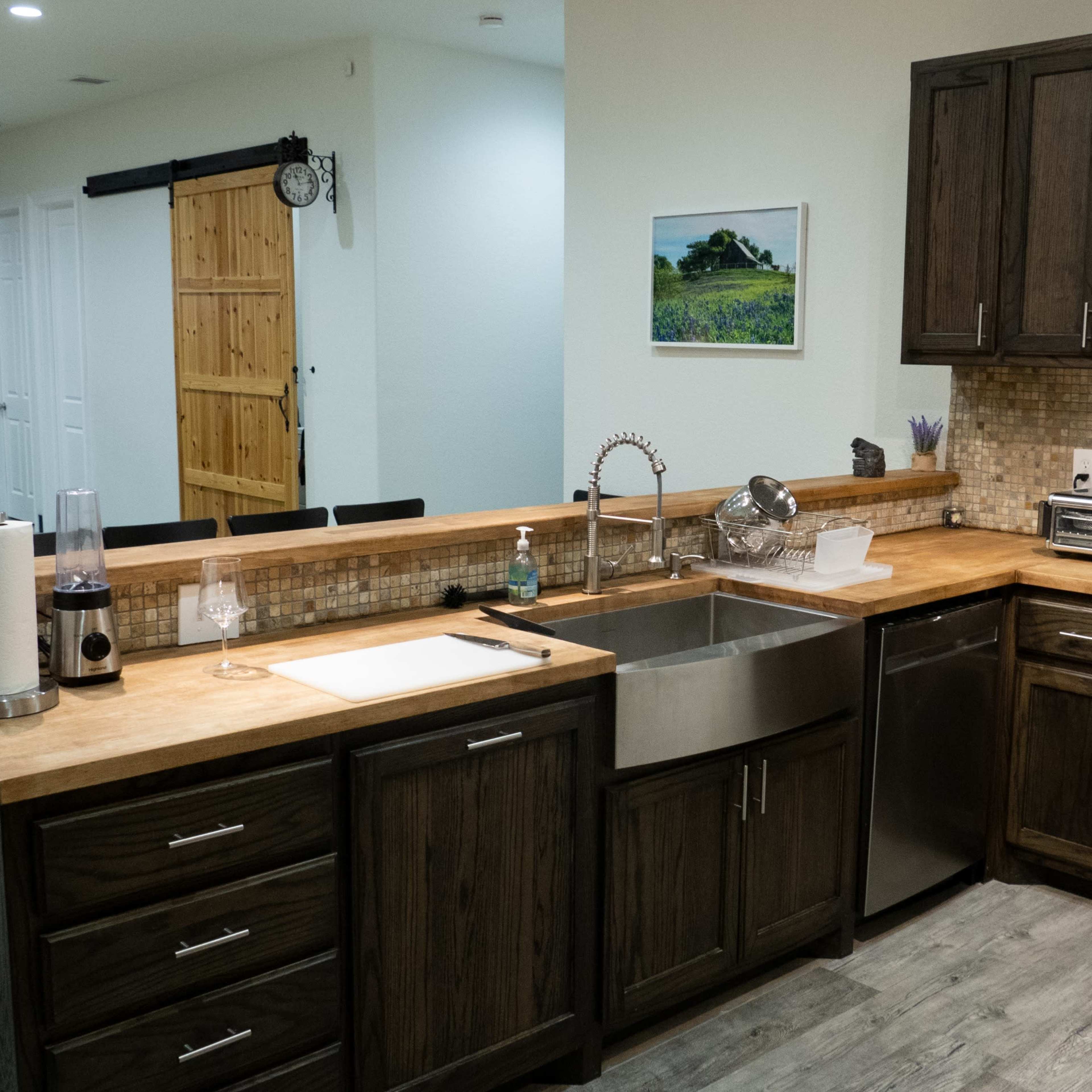 A modern kitchen with dark wooden cabinets, a stainless steel sink, and a countertop made of light-colored wood.