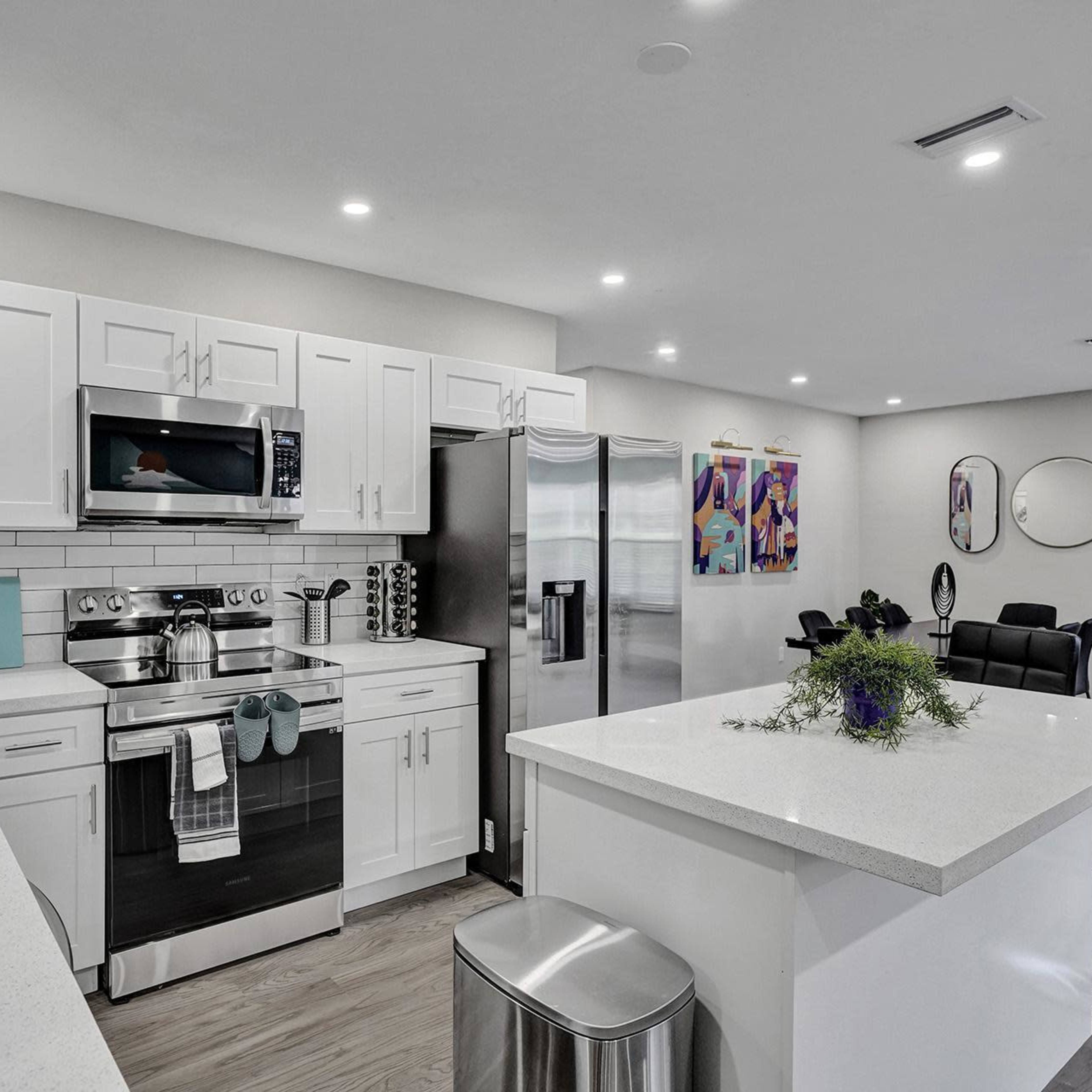 A modern kitchen features white cabinetry, stainless steel appliances, and a centralized island with a small floral arrangement.