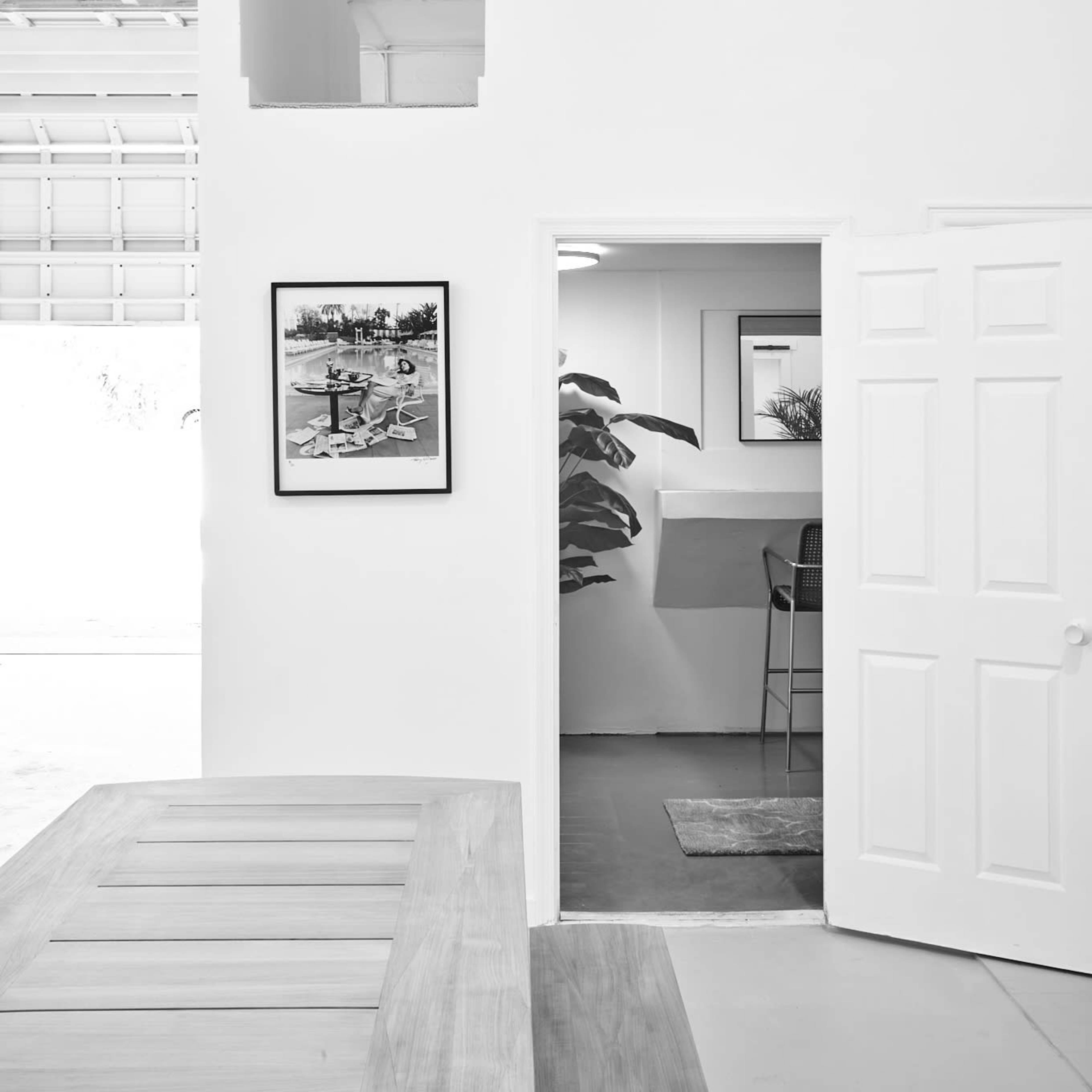 A minimalist interior space with white walls, a doorway leading into another room, and a framed photograph hanging on the wall.