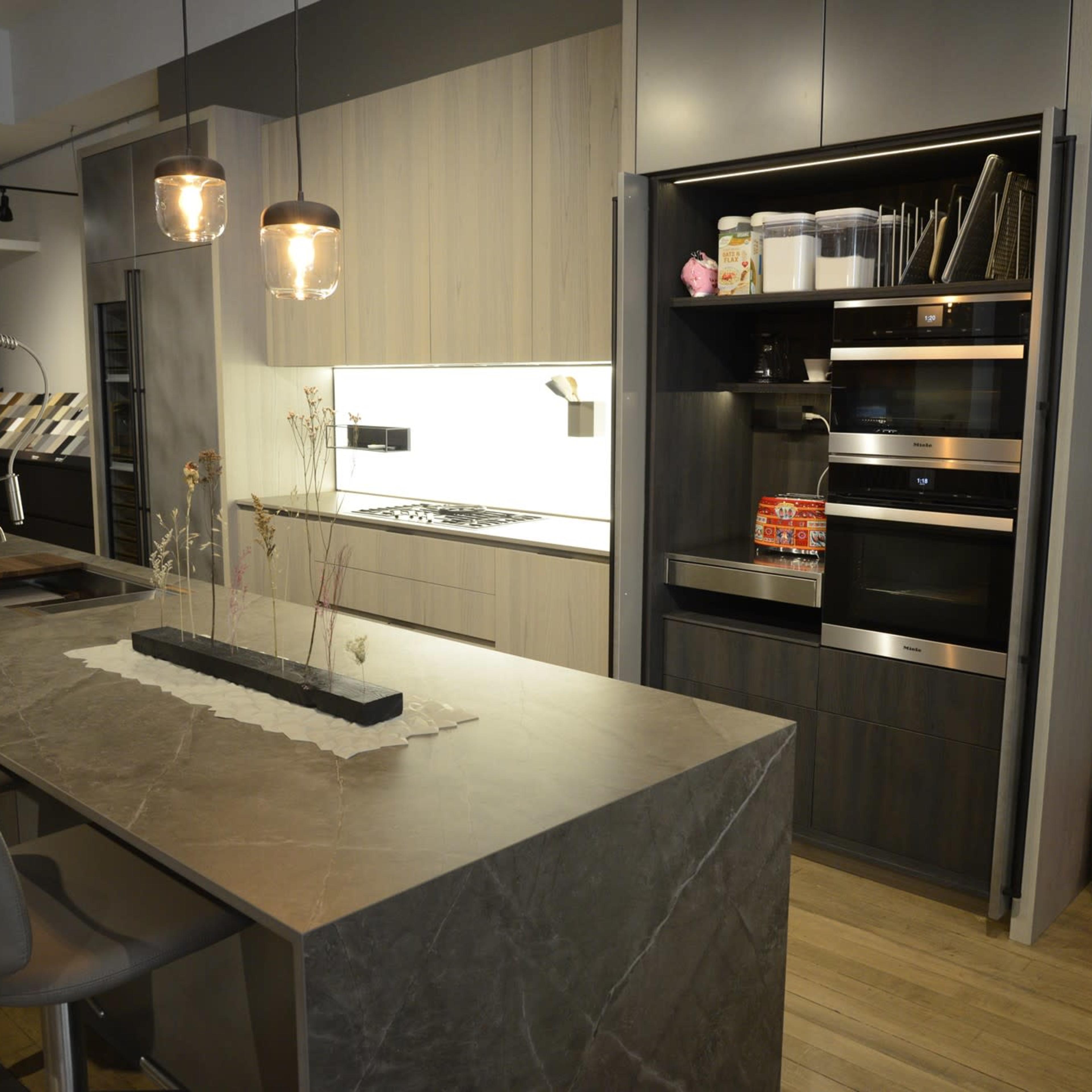 A modern kitchen featuring a large stone island with seating, sleek cabinetry, and built-in appliances.