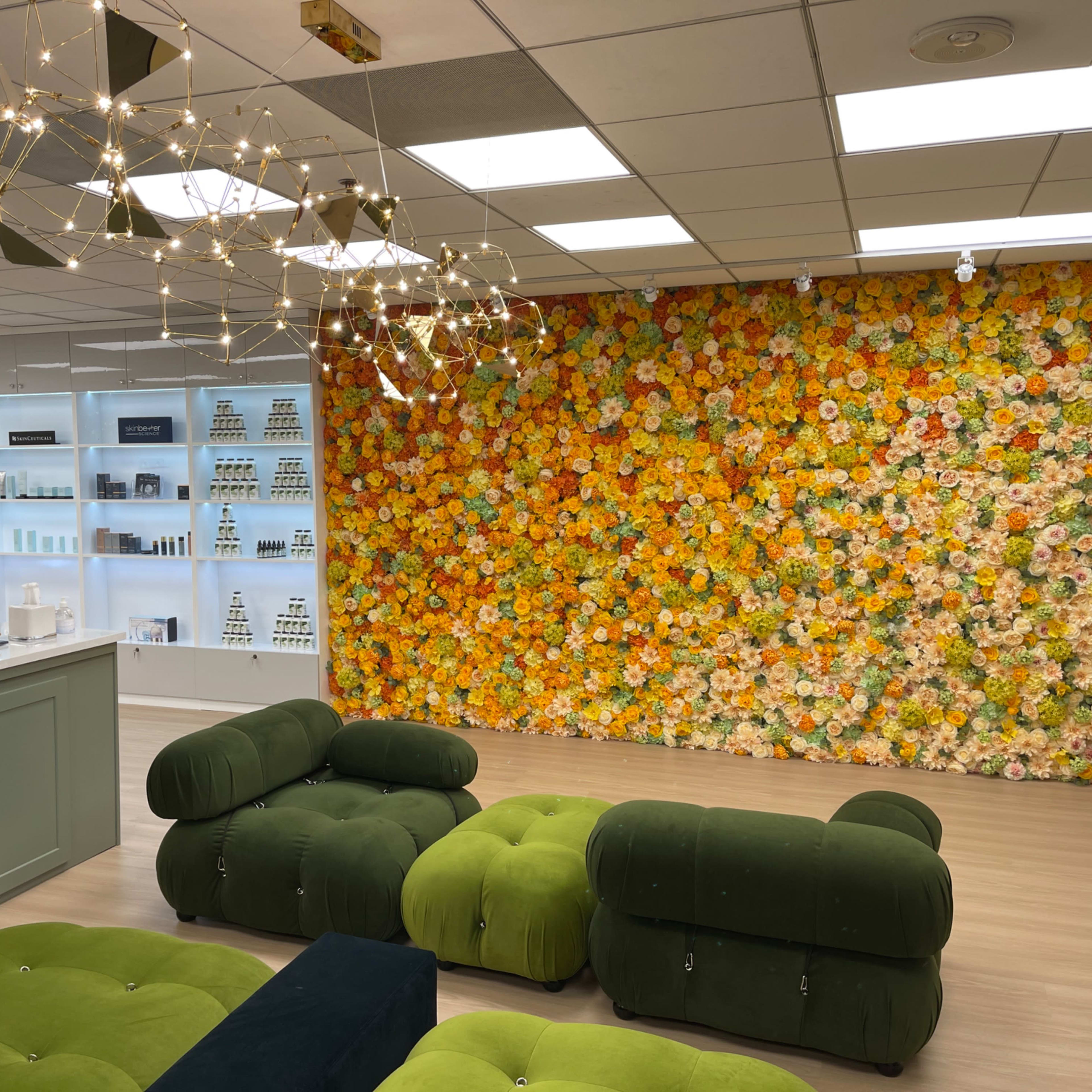 A modern room with a vibrant floral wall, stylish green tufted seating, and shelves displaying various products.