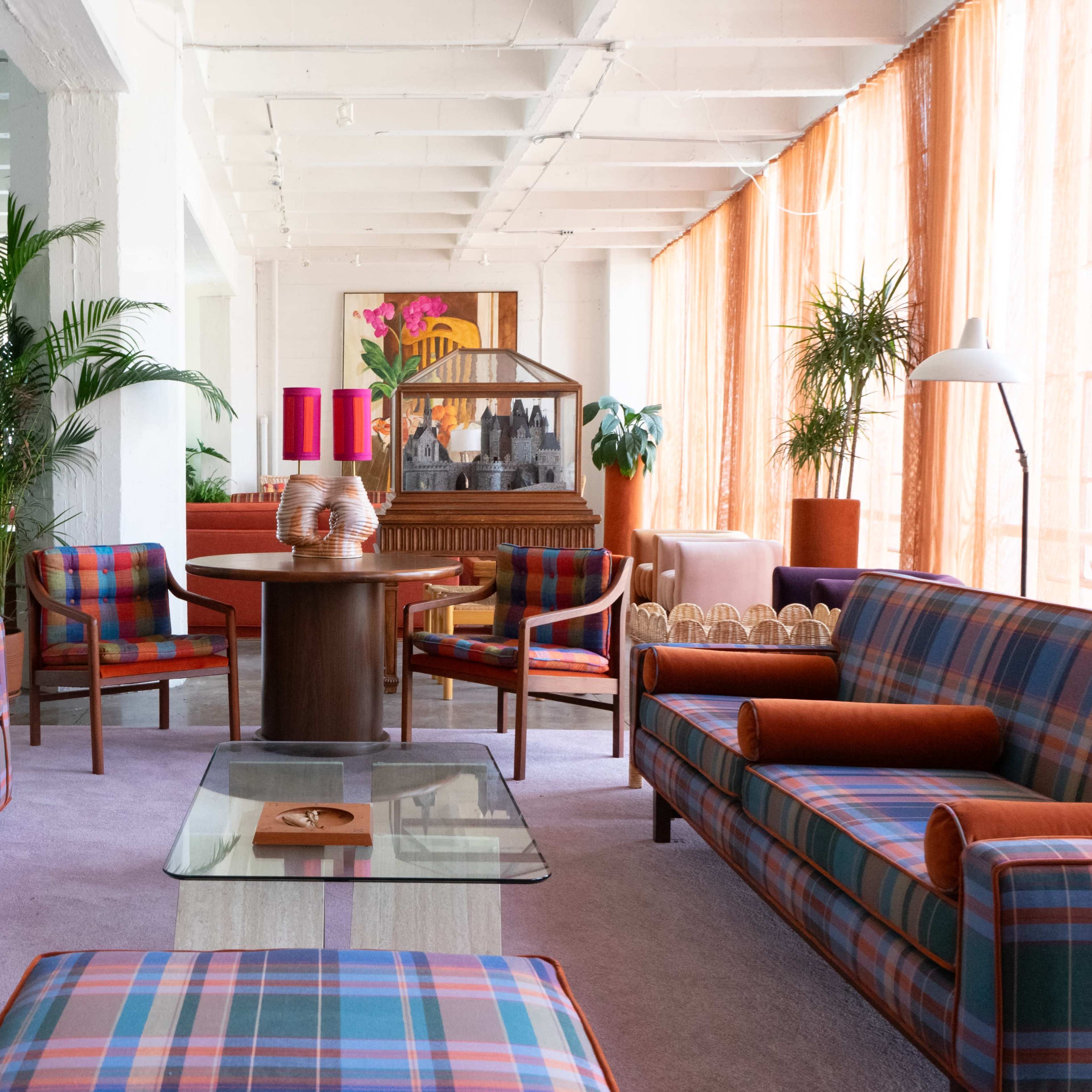 A modern interior space featuring plaid-patterned furniture, a round wooden table, and vibrant plants, all arranged for a contemporary aesthetic.