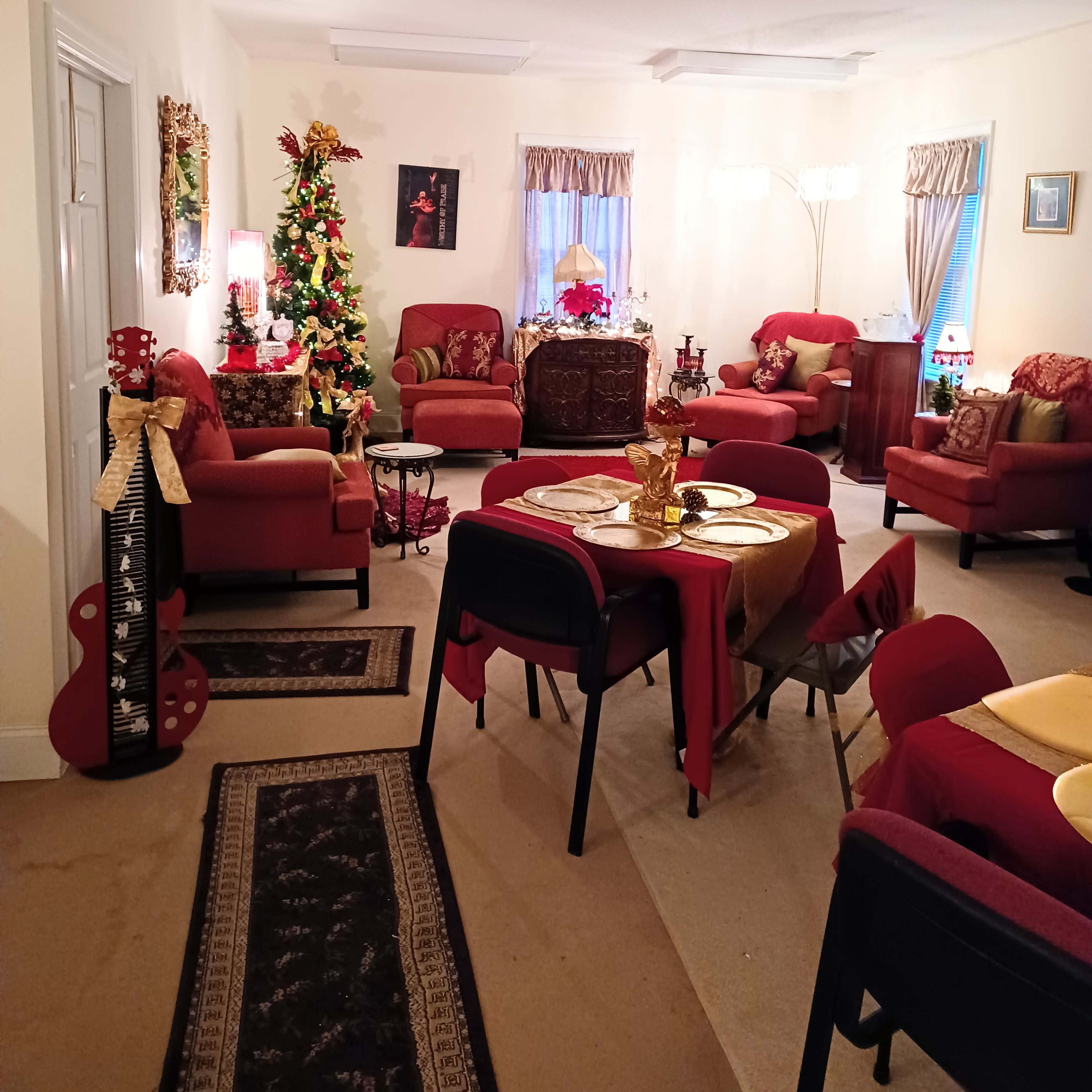 A decorated living room with red furniture, a Christmas tree, and a dining table set for a meal.
