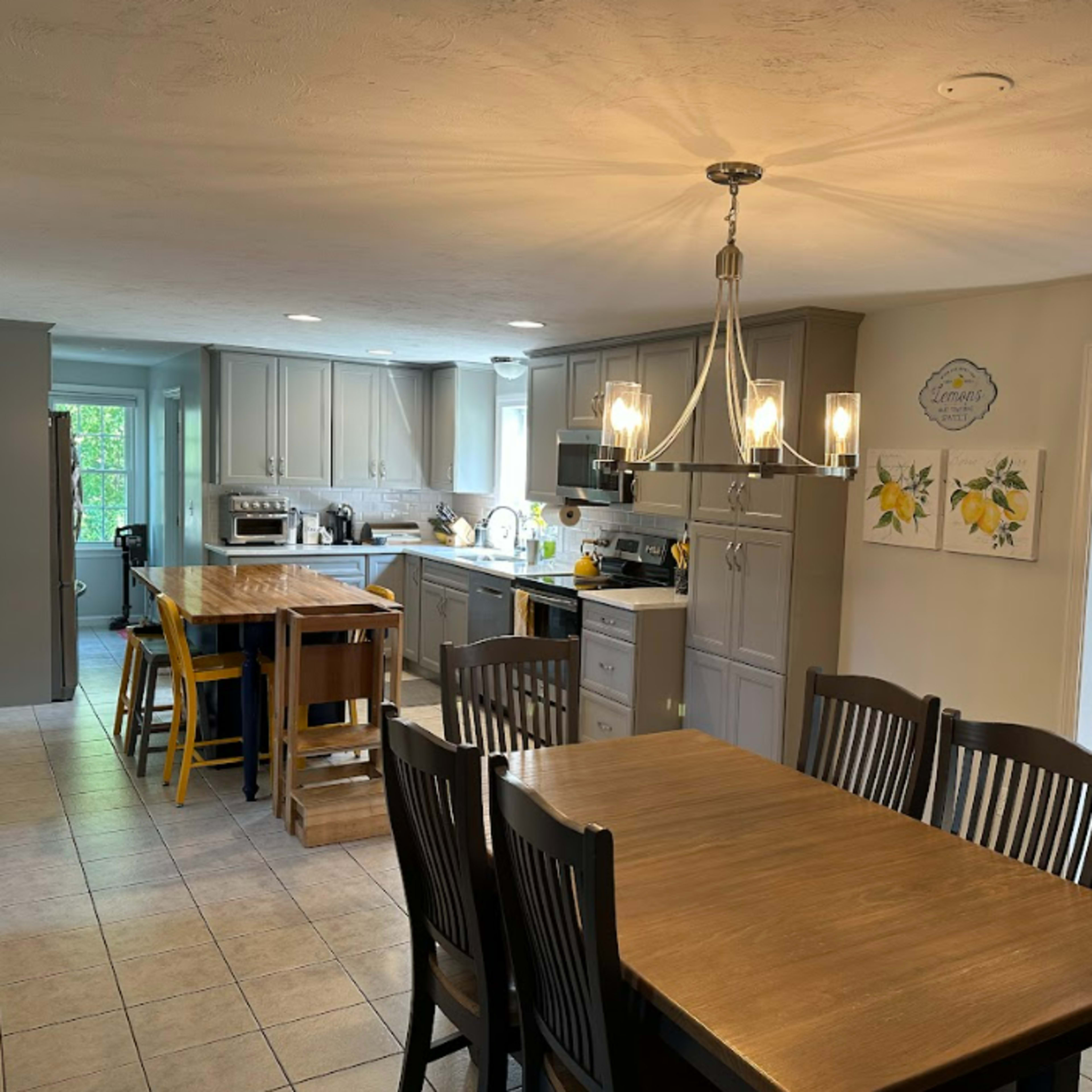 A spacious kitchen and dining area features gray cabinets, a central island with stools, and a dining table set for several.