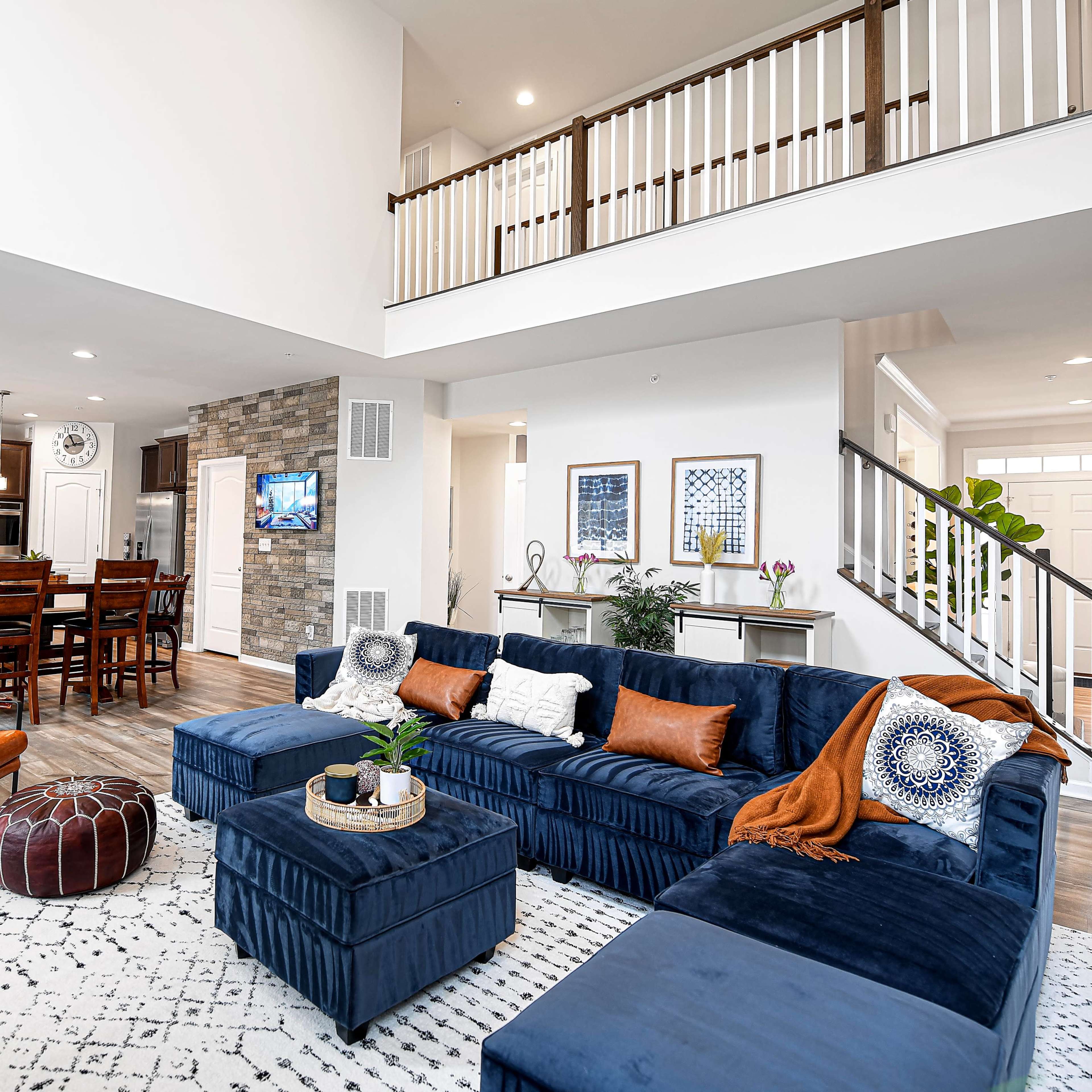 A modern living room with a navy blue sectional sofa, a coffee table, and a view of an open kitchen and dining area in the background.