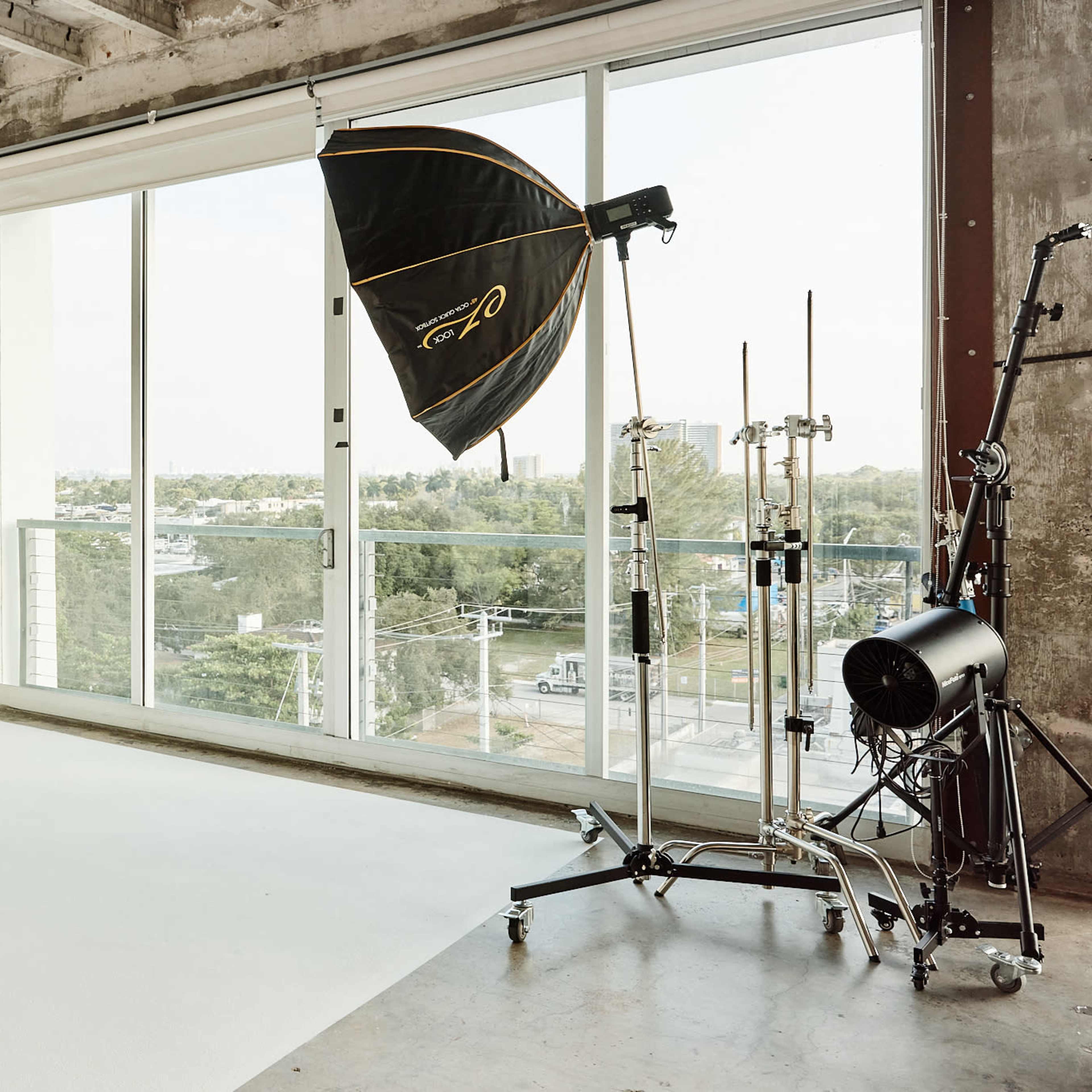 A photography studio with a large softbox light positioned near a window overlooking a cityscape.