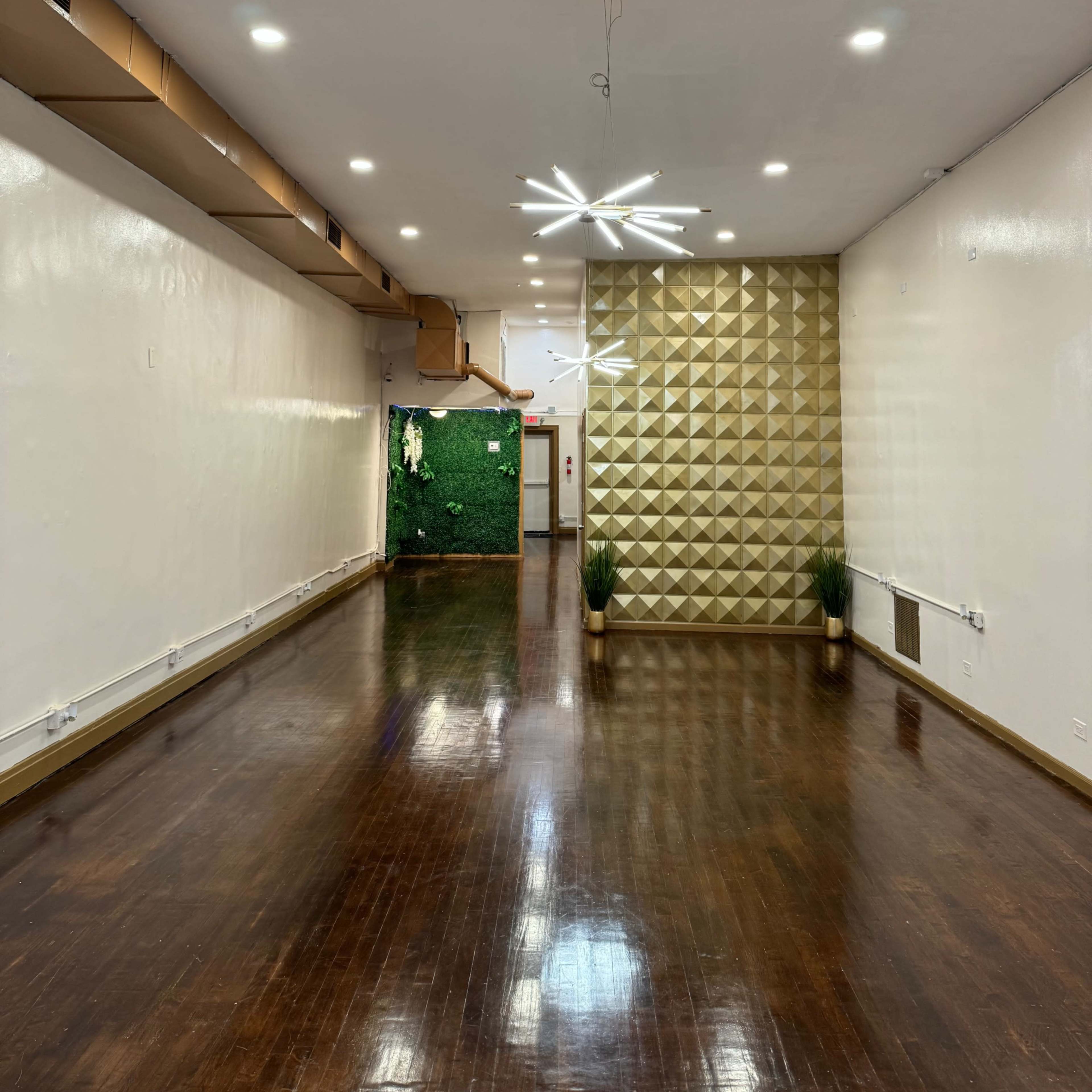 A spacious, well-lit room featuring a textured gold accent wall and dark hardwood flooring.