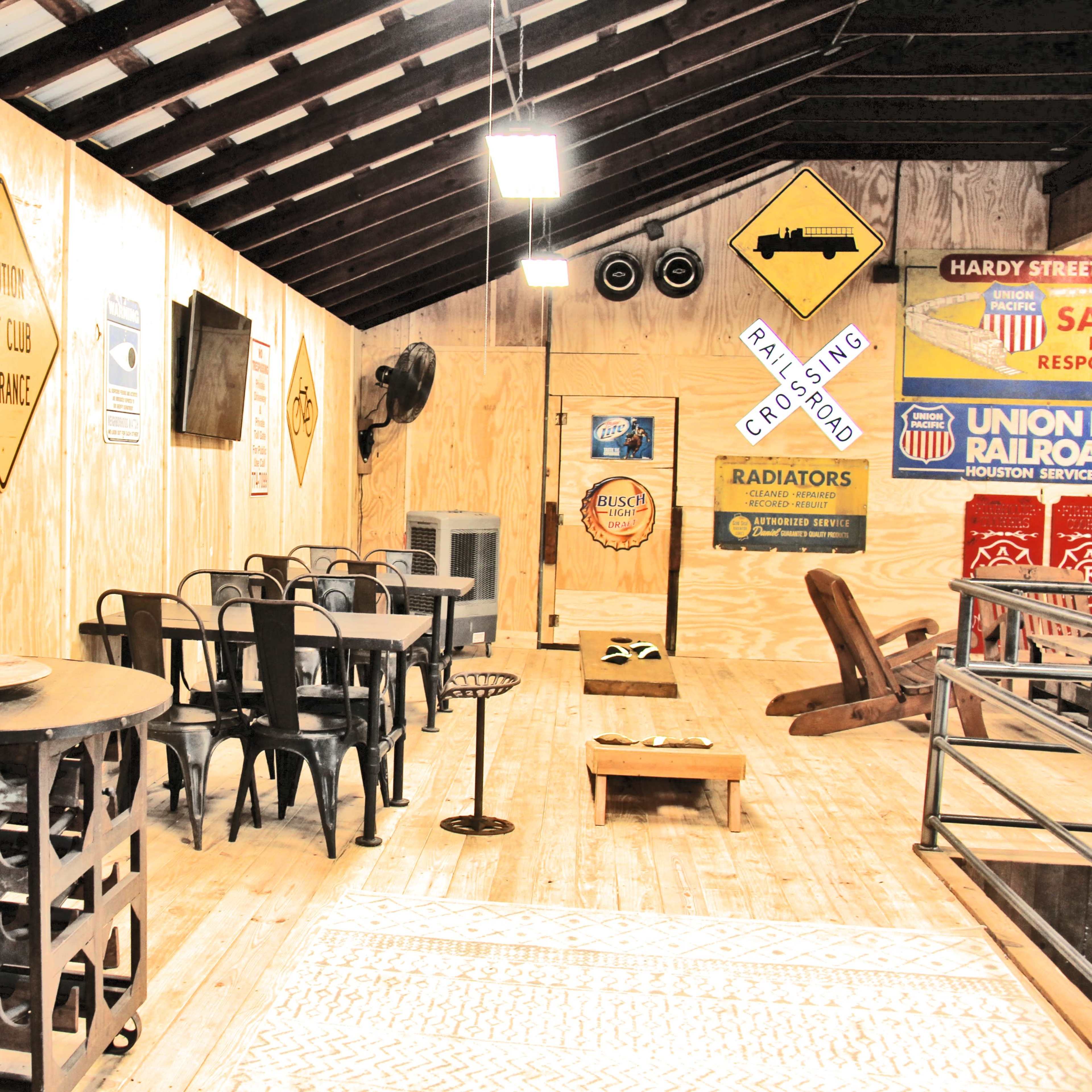 The interior of a wooden building features a dining area with metal chairs, a table, a vintage decoration setup, and wooden flooring.