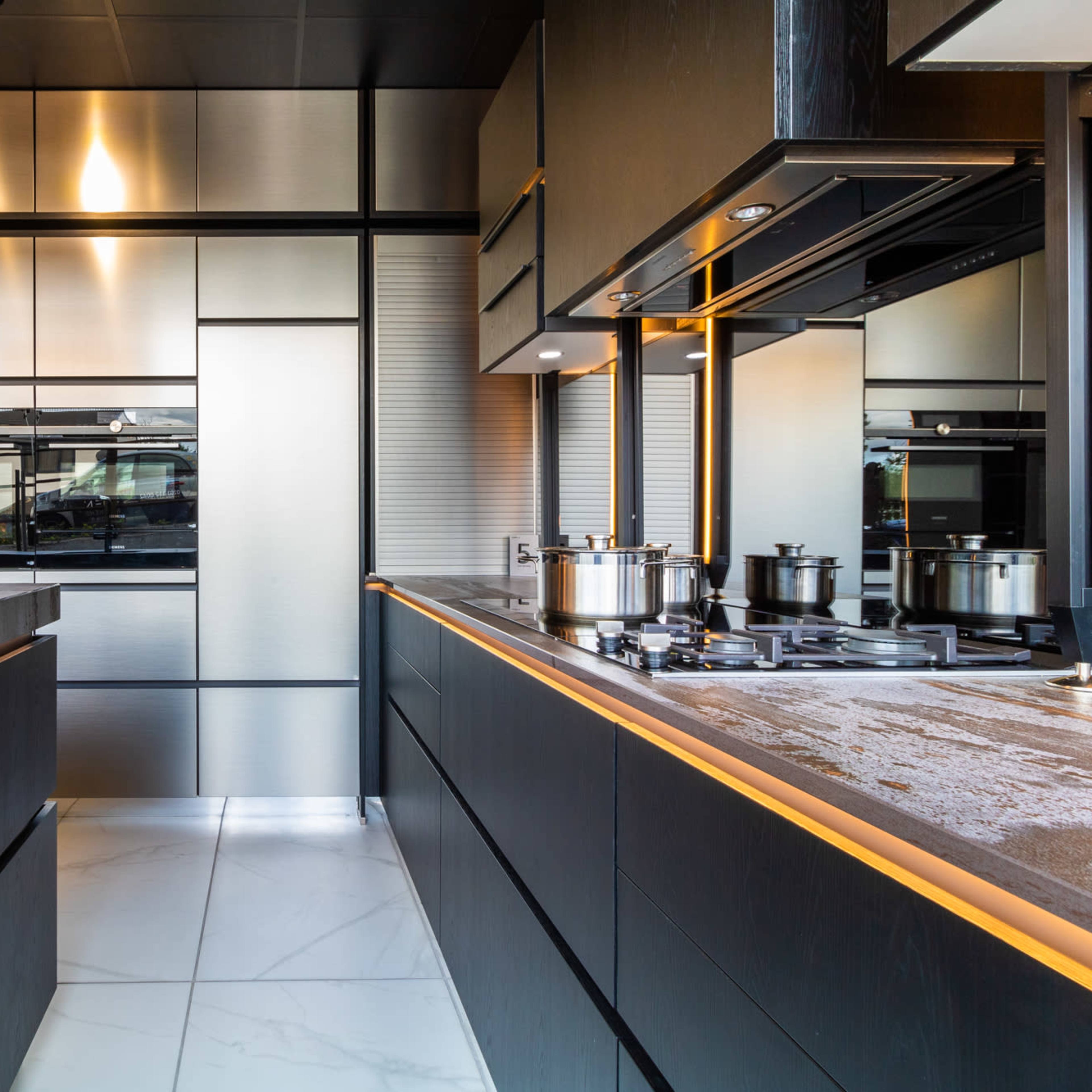 A modern kitchen with sleek, dark cabinetry, stainless steel appliances, and a contrasting light countertop.