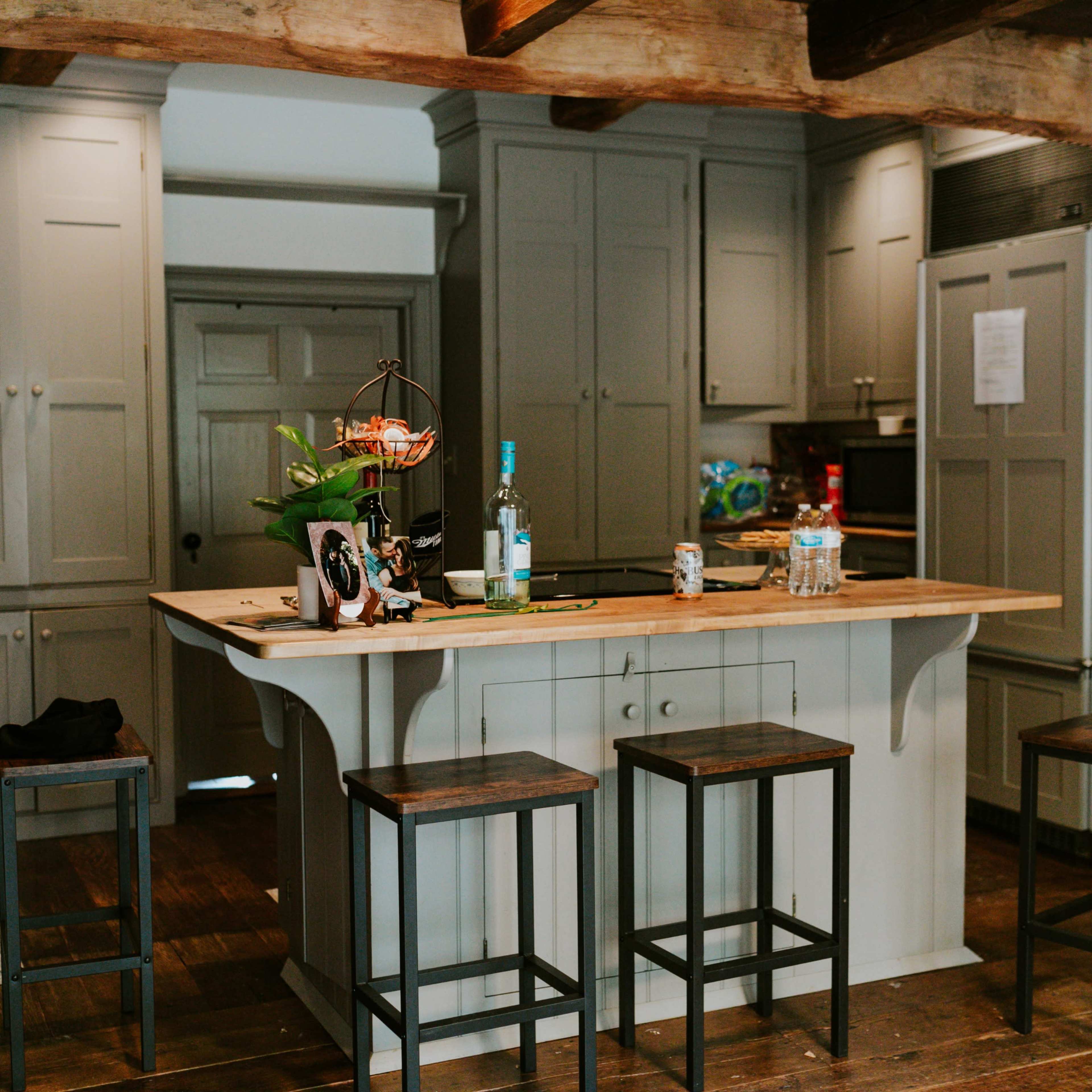 The kitchen features a central island with bar stools, grey cabinetry, and stainless steel appliances.