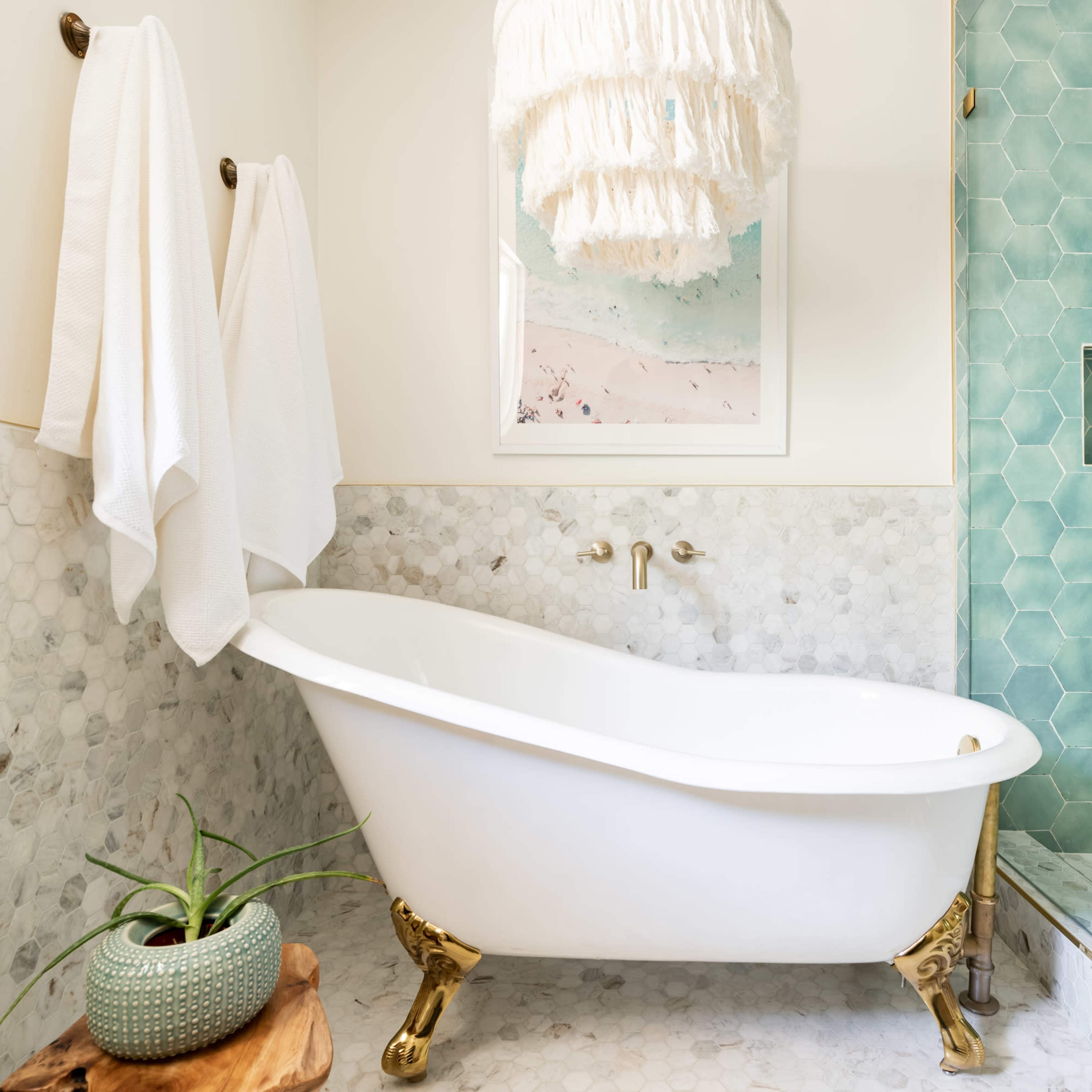 A bathroom featuring a clawfoot bathtub, a fringed pendant light, and teal hexagonal tiles in the shower area.