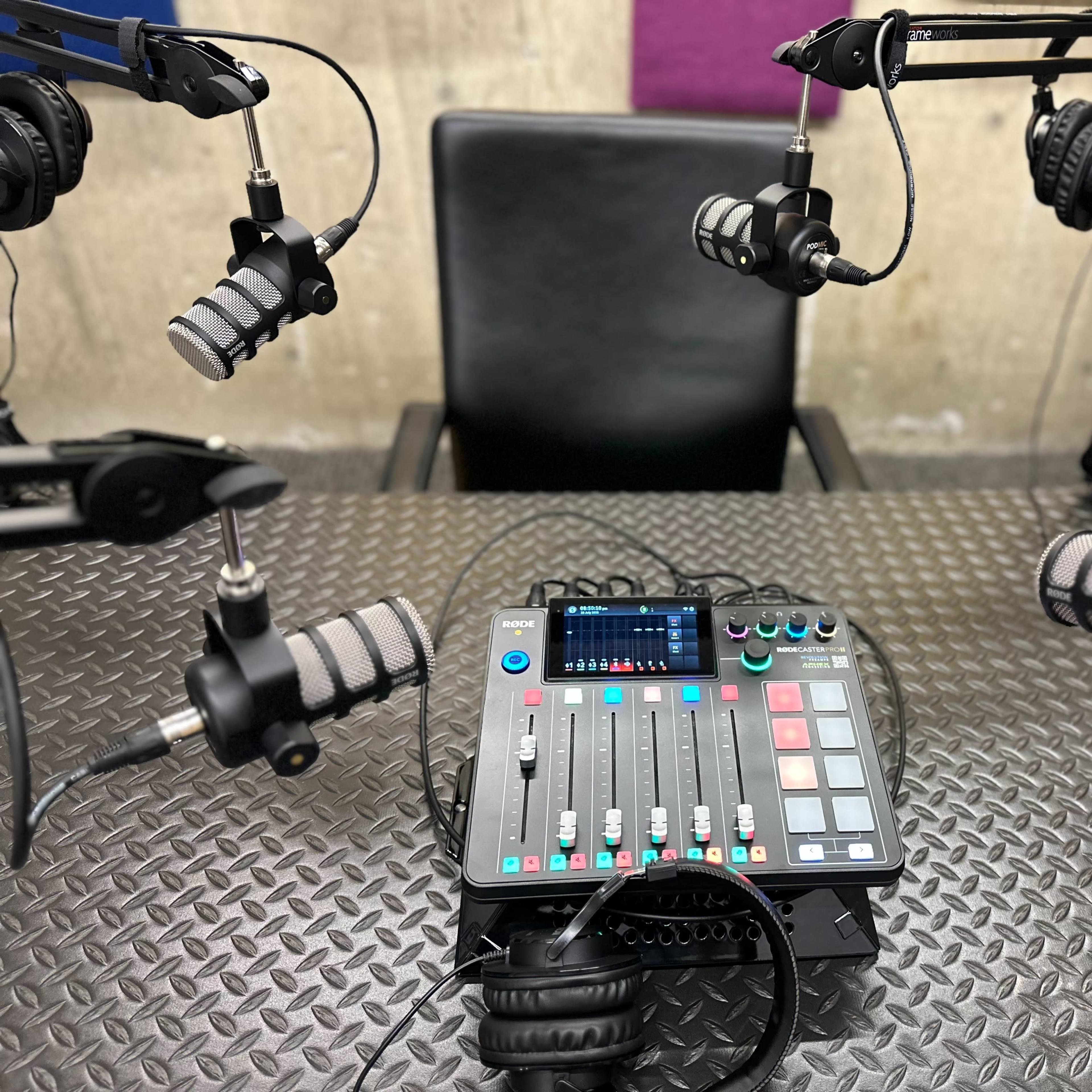 A control panel with microphones is set up in a recording studio next to a chair.