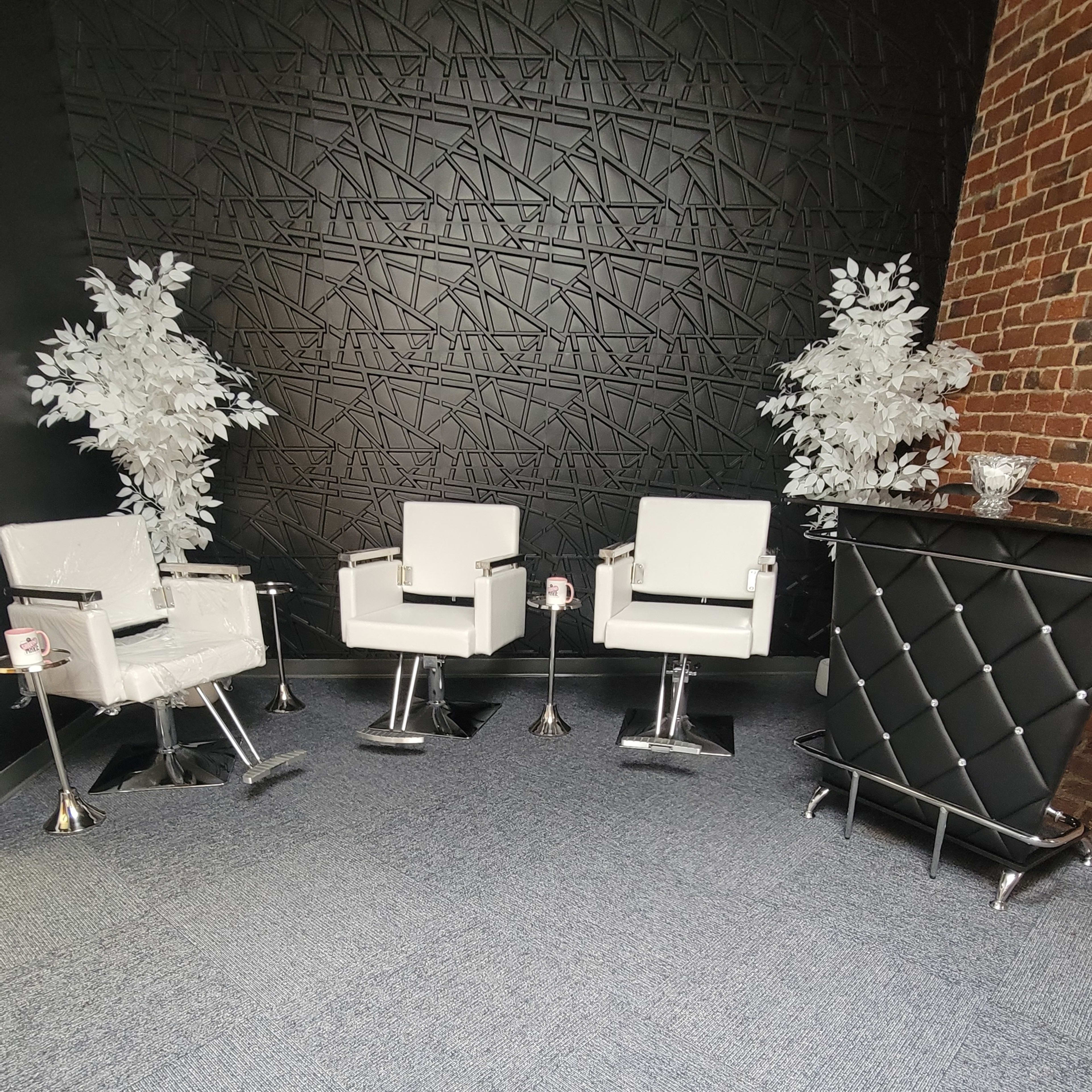 A modern interior with white chairs and a black decorative wall, featuring two artificial white trees and a black reception desk.