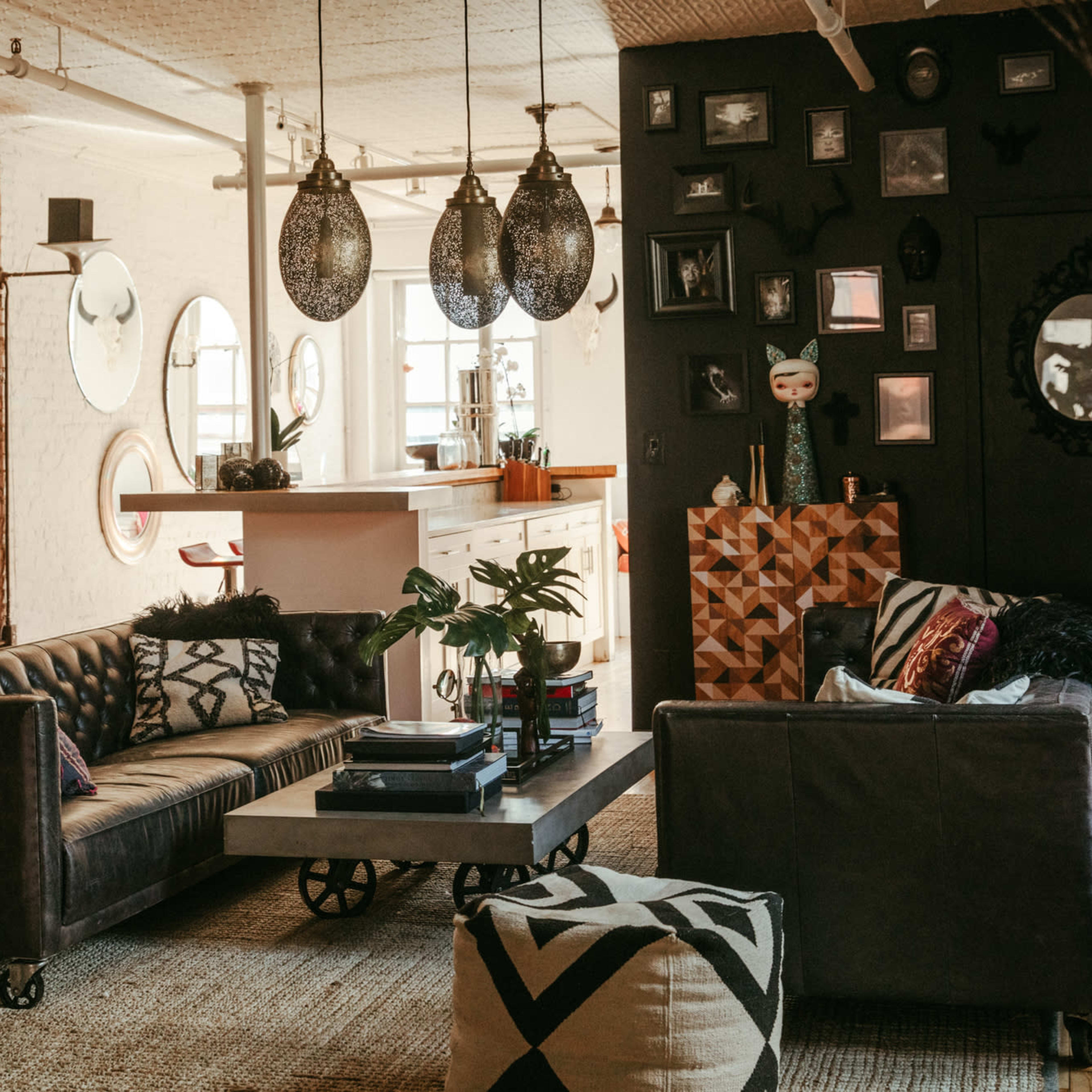 A cozy, industrial-style living room with exposed brick walls, modern furniture, and decorative elements, including pendant lights and art pieces.