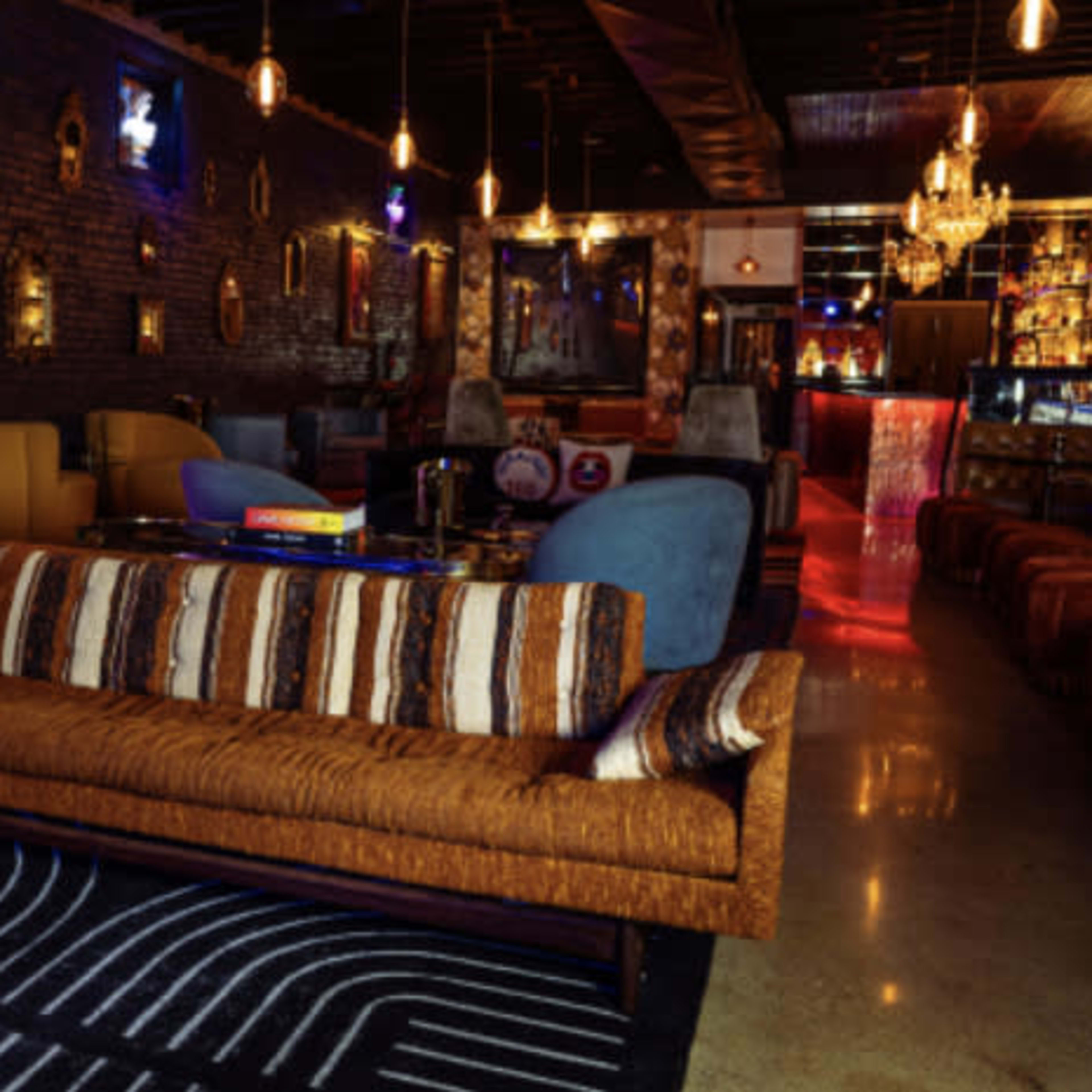 A stylish lounge with colorful seating, a bar area, and decorative lighting.