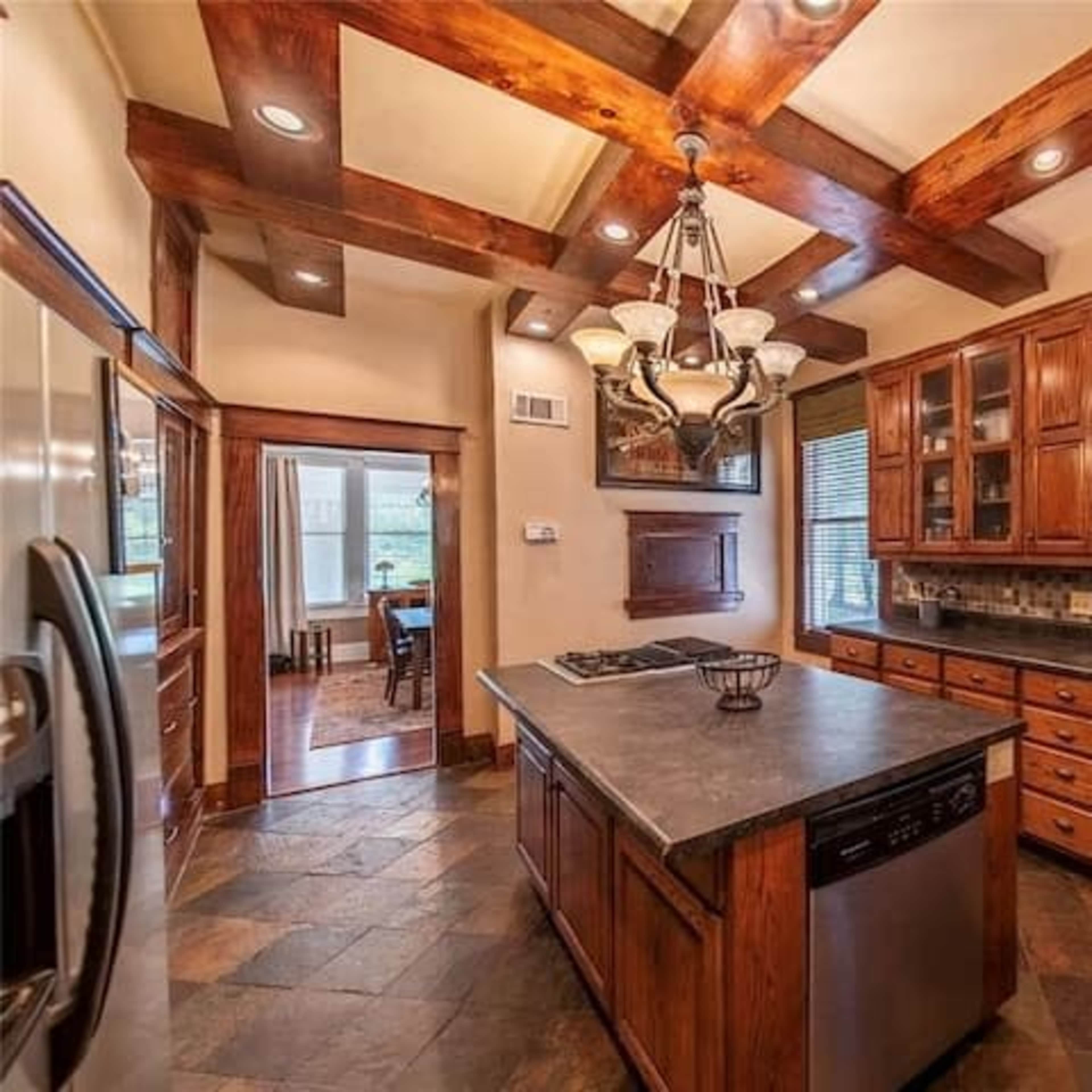 A spacious kitchen featuring wooden cabinets, a large island, and a mix of stone and tile flooring.