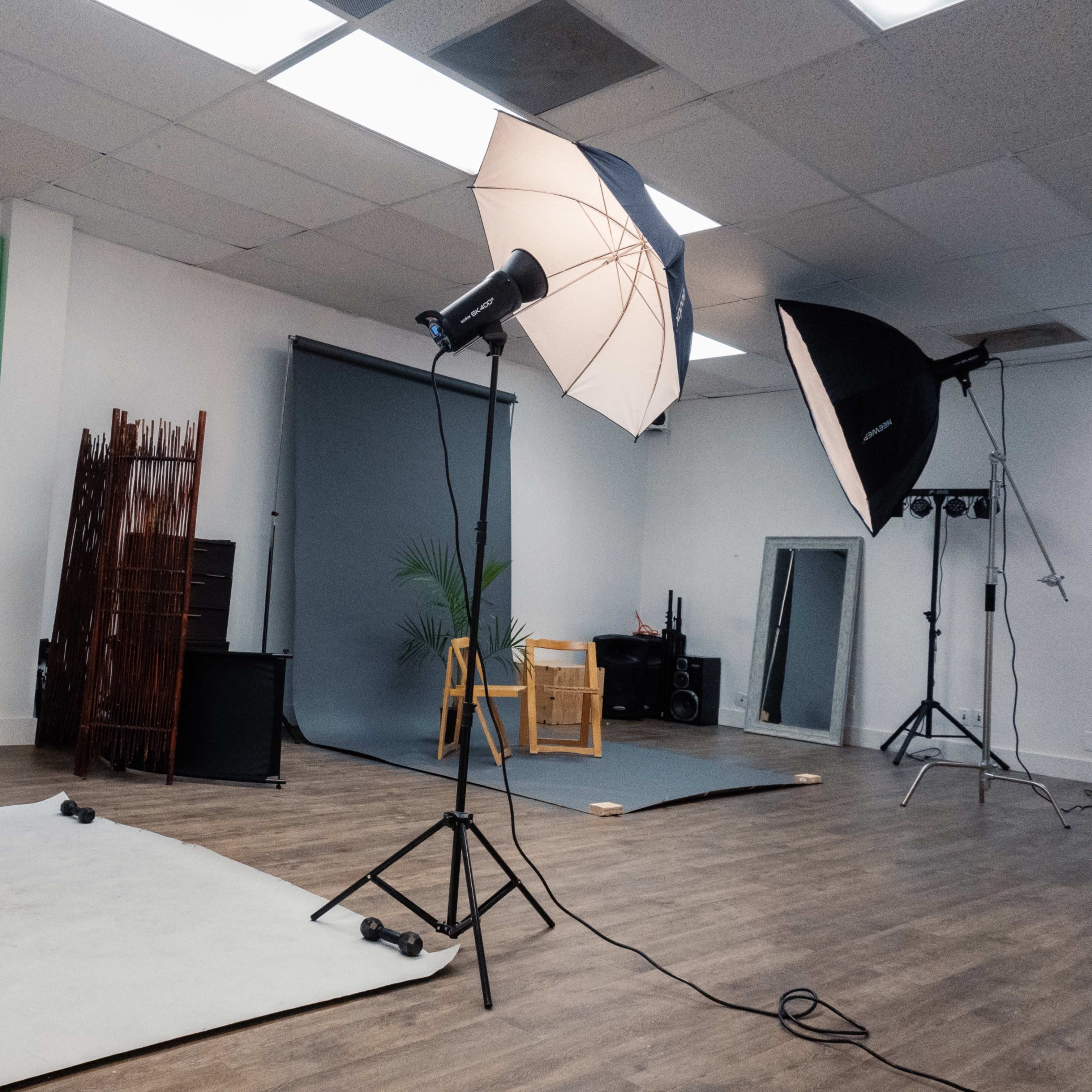 A photography studio with various lighting setups, backdrops, and props arranged on the floor.