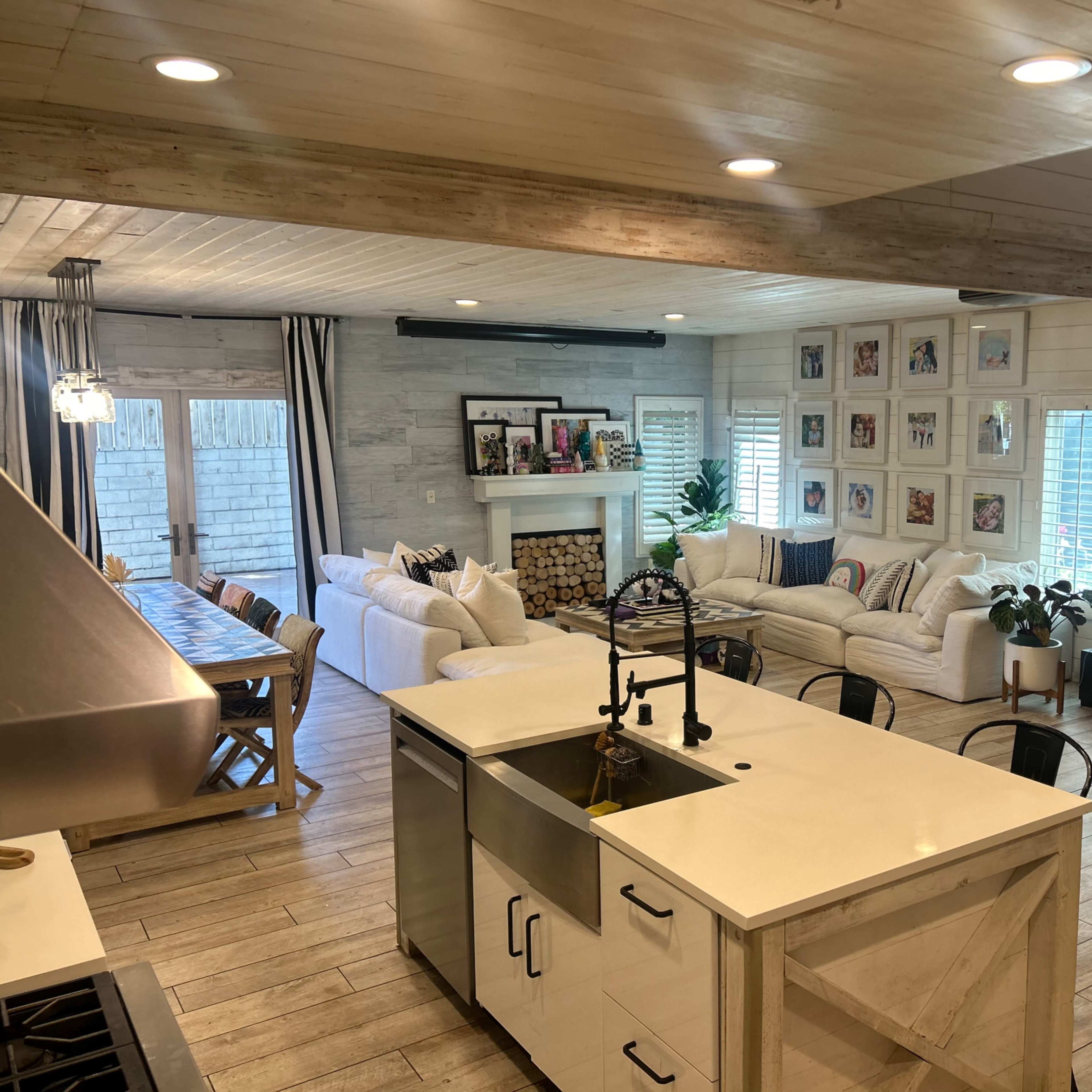 A bright, open-concept living area featuring a living room with a sofa, a dining area with a long table, and a spiral staircase leading to an upper level.