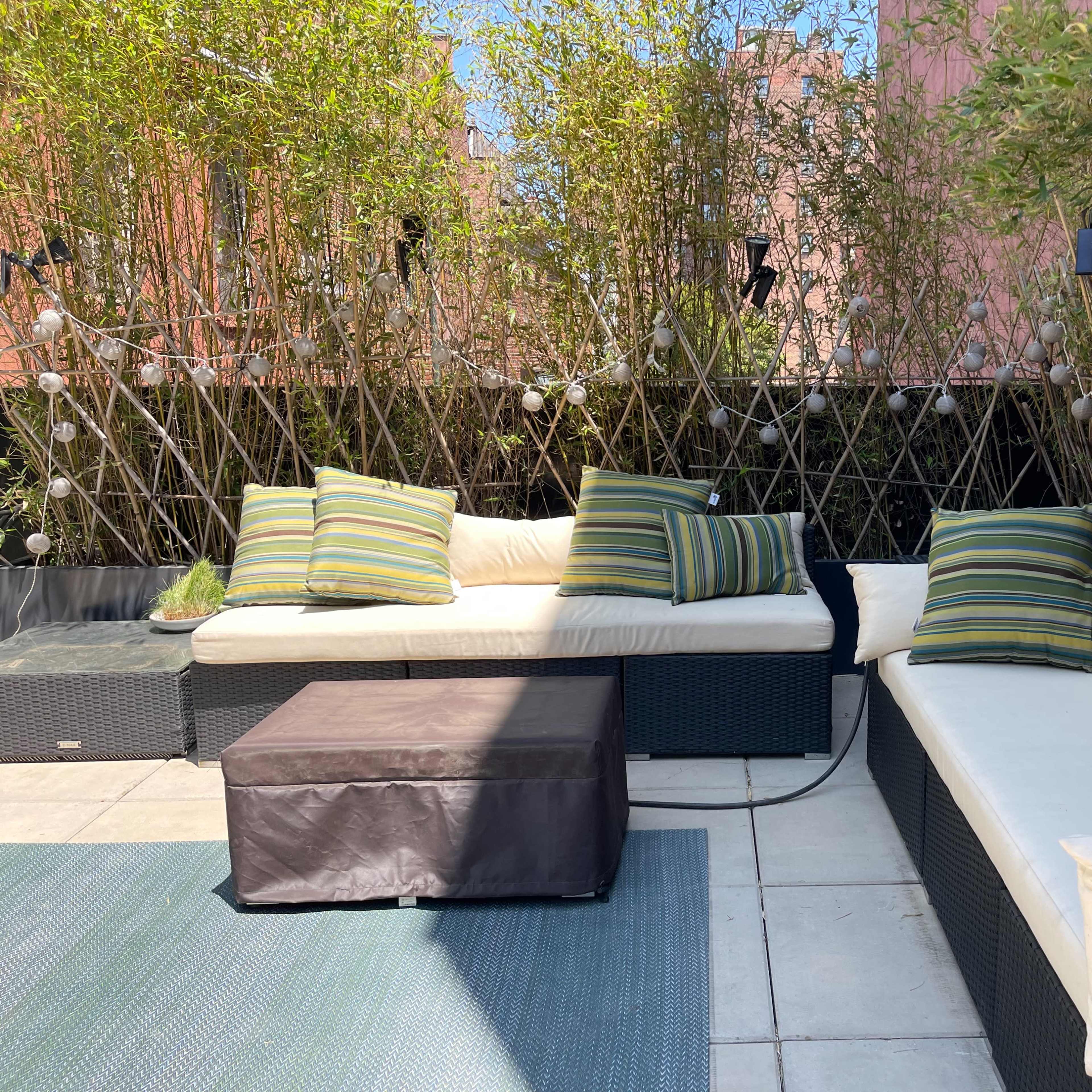 A patio area features two modern, cushioned seating sections surrounded by bamboo and string lights.